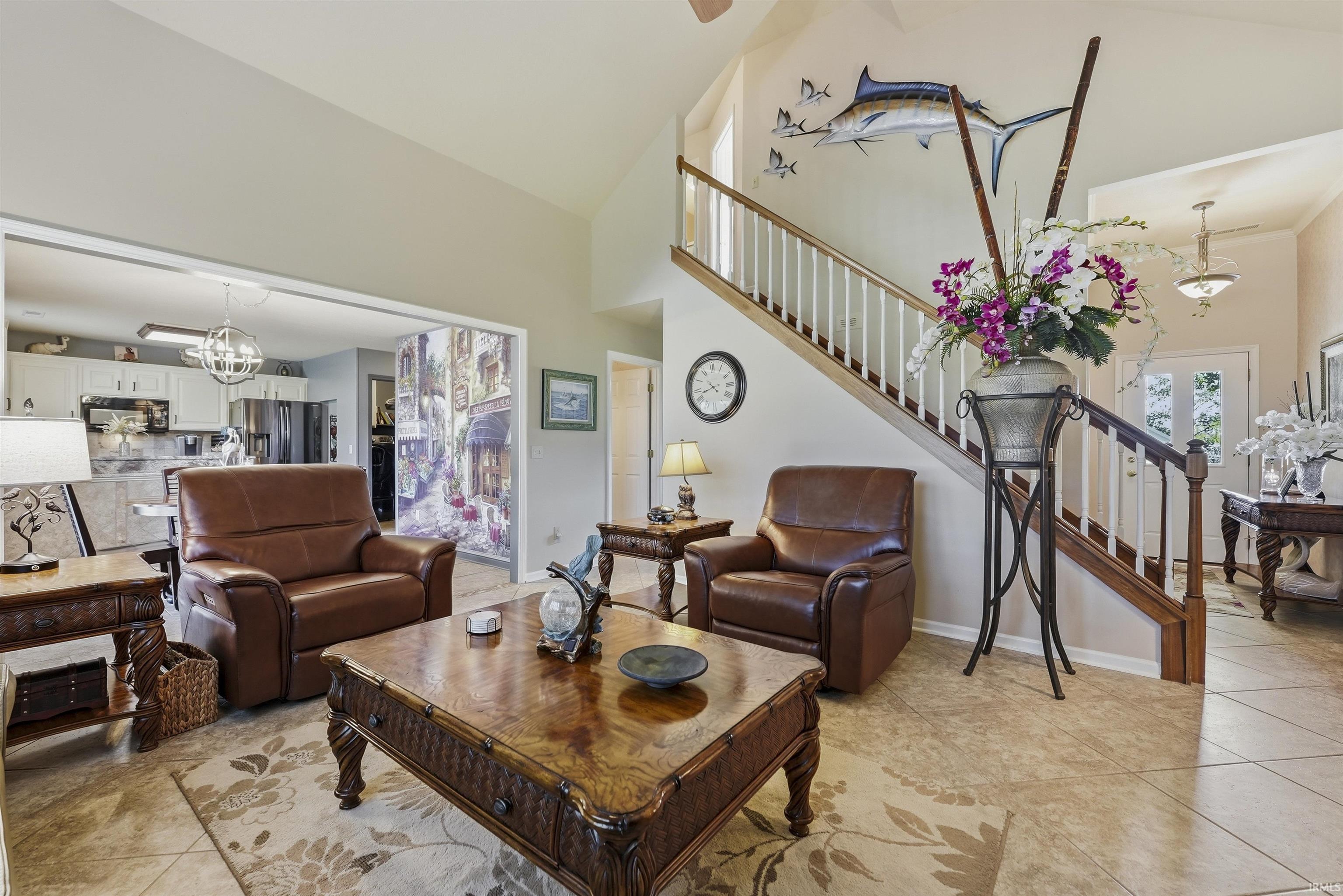 Spacious open-concept living area featuring dual leather recliners, ornate wood-finish coffee table, and neutral tile flooring