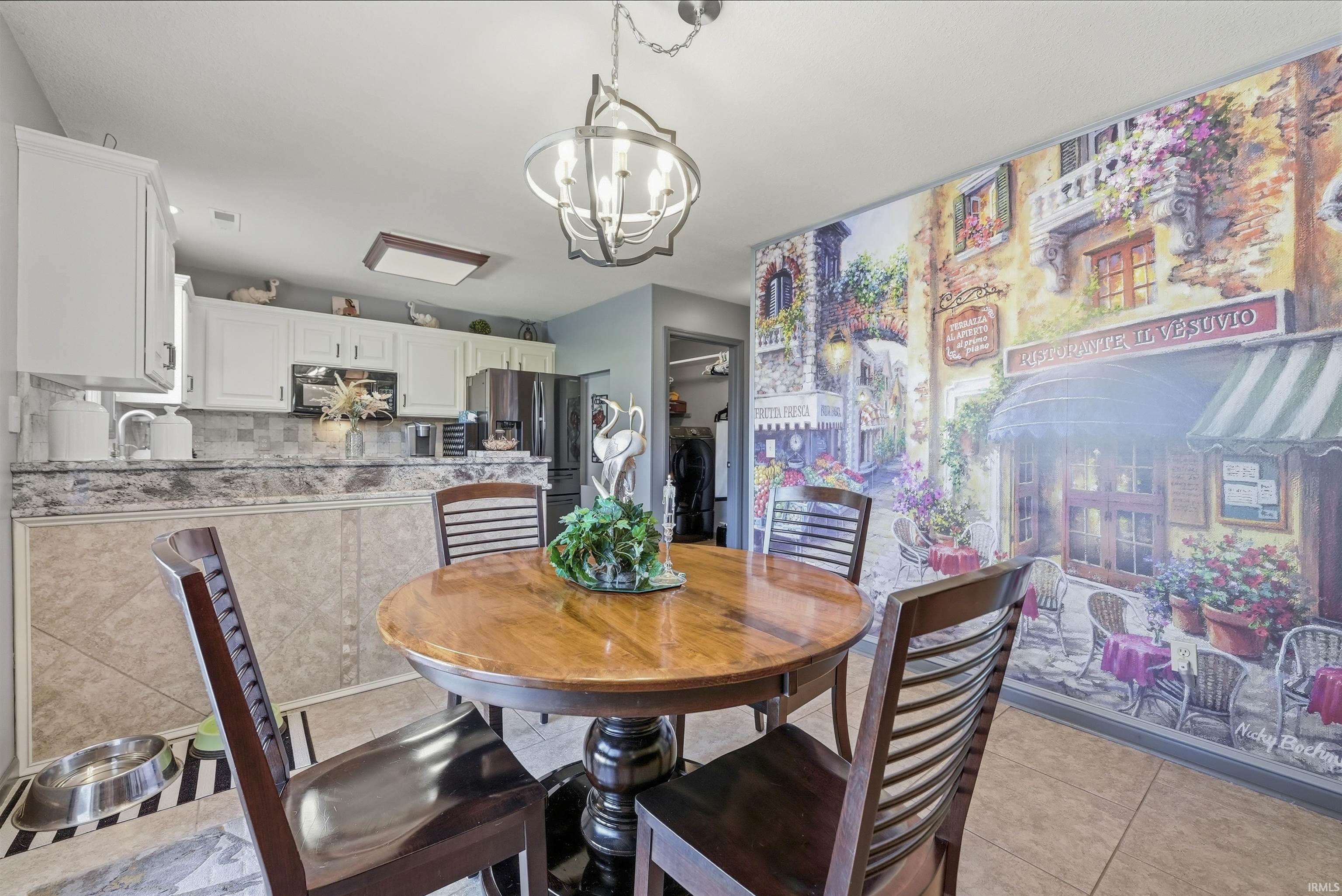 Charming dining area featuring a round wood pedestal table with coordinating ladder-back chairs, ceramic tile flooring, and a geometric pendant light fixture