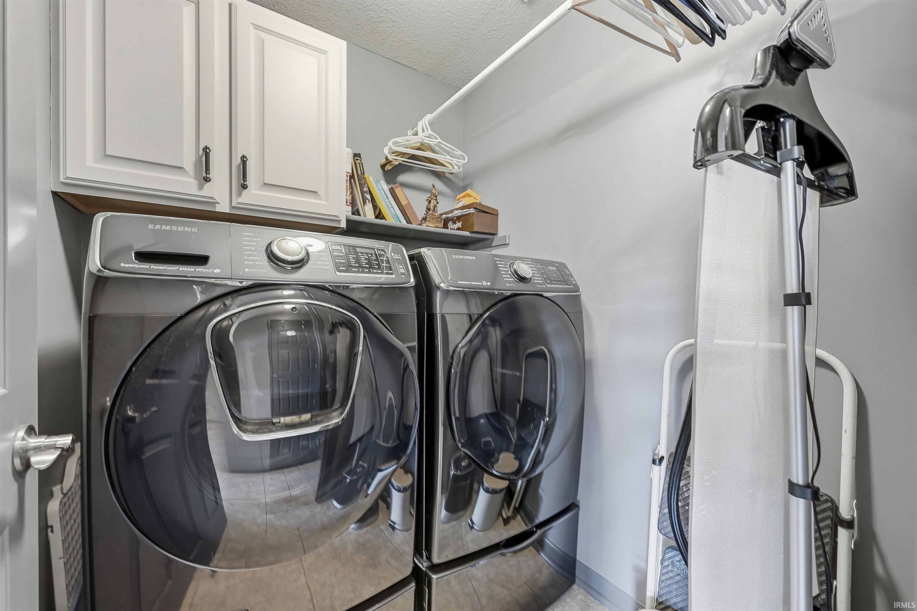 Modern laundry room featuring side-by-side washer and dryer with large-capacity drums, digital controls, and sleek stainless steel finishes