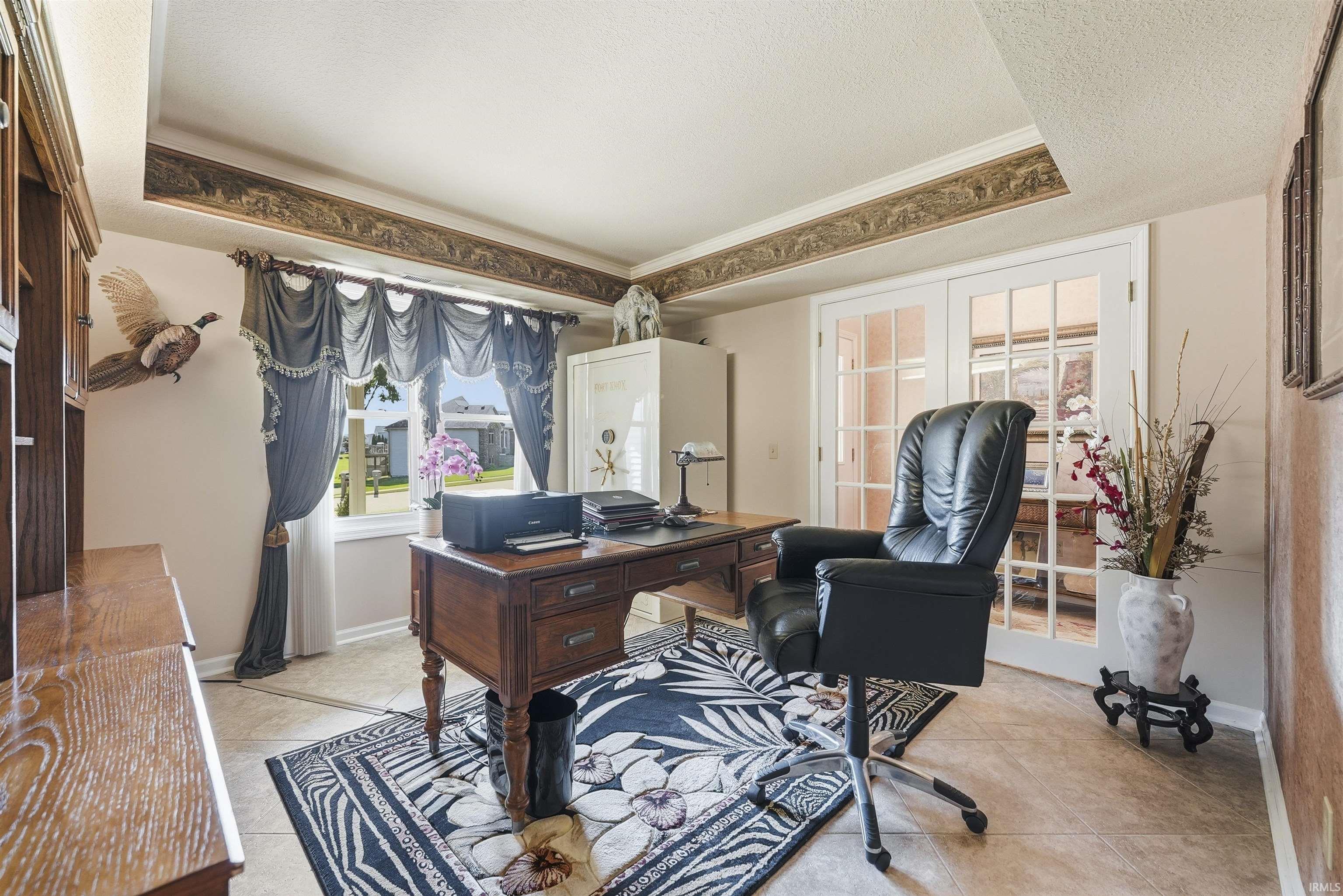 Elegant home office featuring a traditional wood desk, black leather executive chair, and hardwood flooring anchored by a geometric area rug