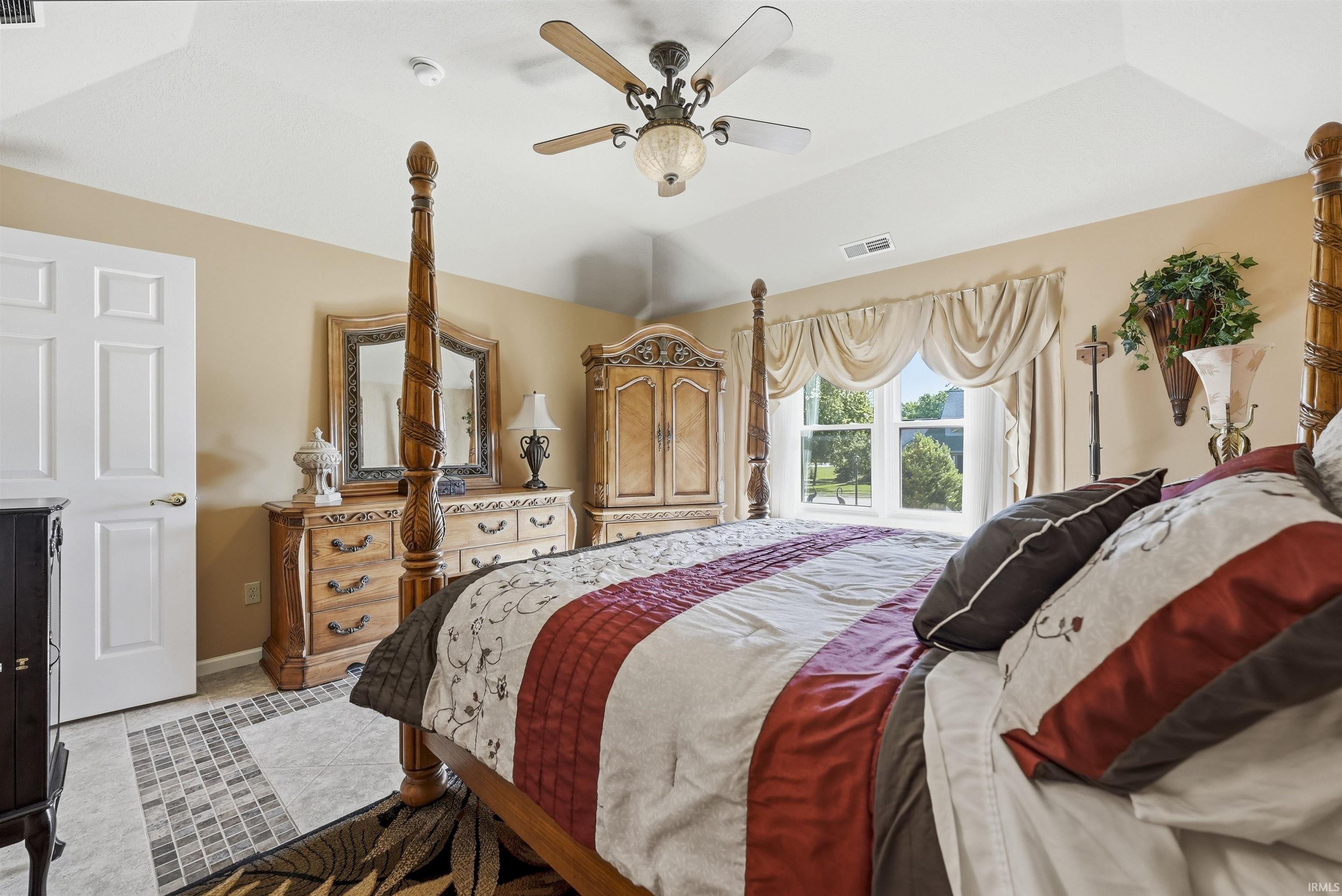 Room featuring a tray ceiling with a ceiling fan light fixture, light-colored walls, and a window with a valance and drapery