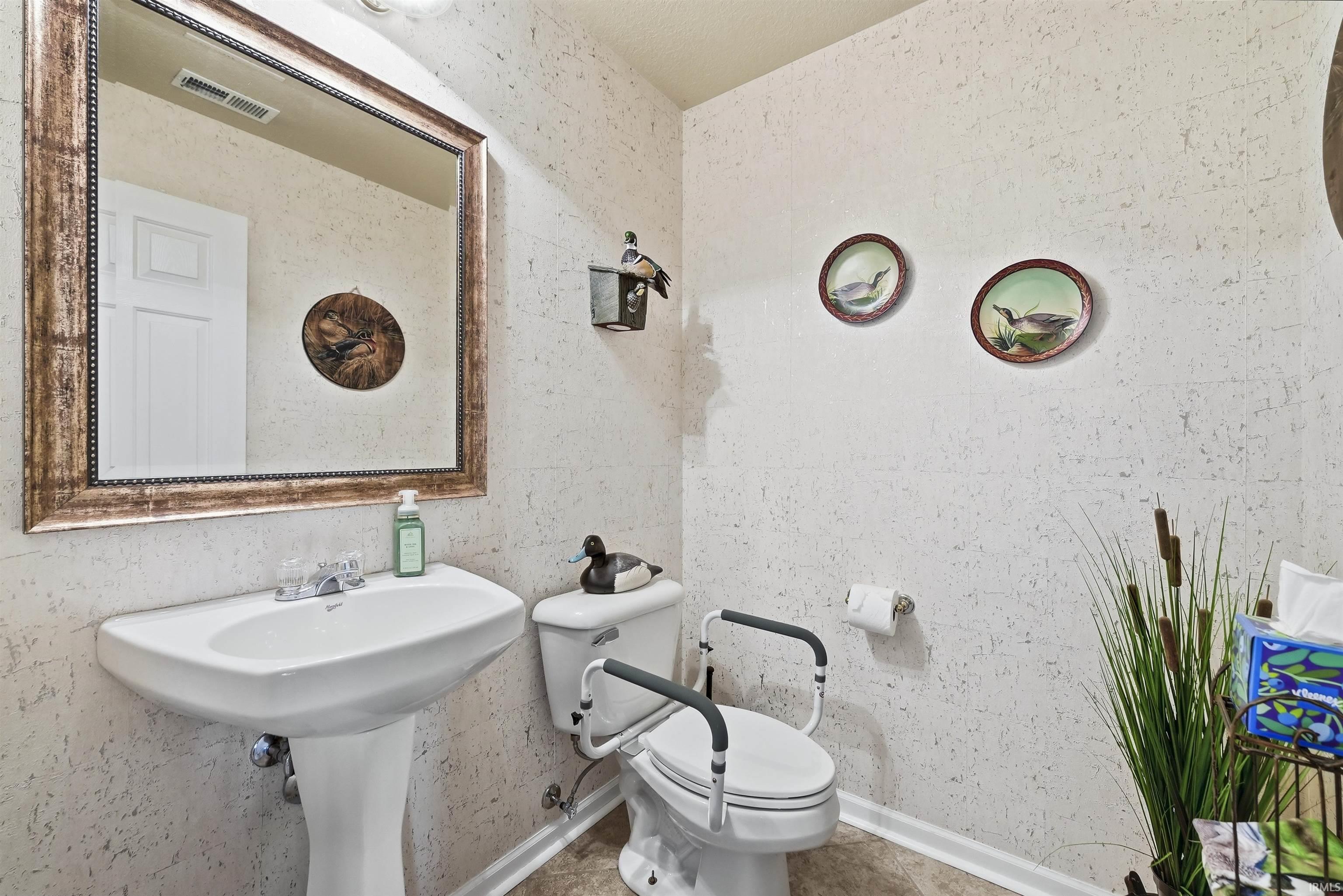 Charming half bath featuring a pedestal sink with chrome faucet, white ceramic toilet, and textured neutral wall finishes
