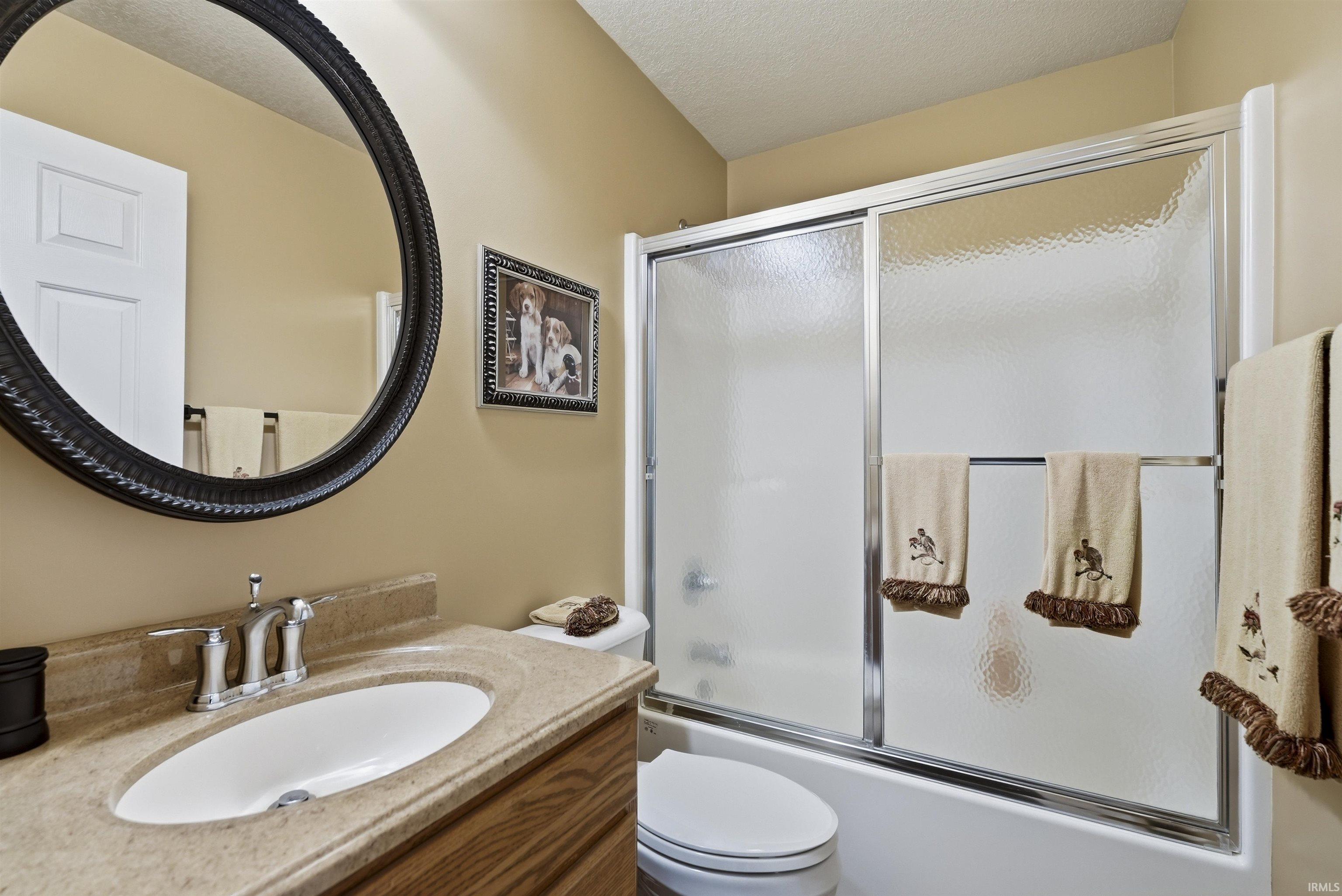 Spa-inspired bathroom featuring a wood-finish vanity with an oval undermount sink, chrome faucet fixture, and ample counter space