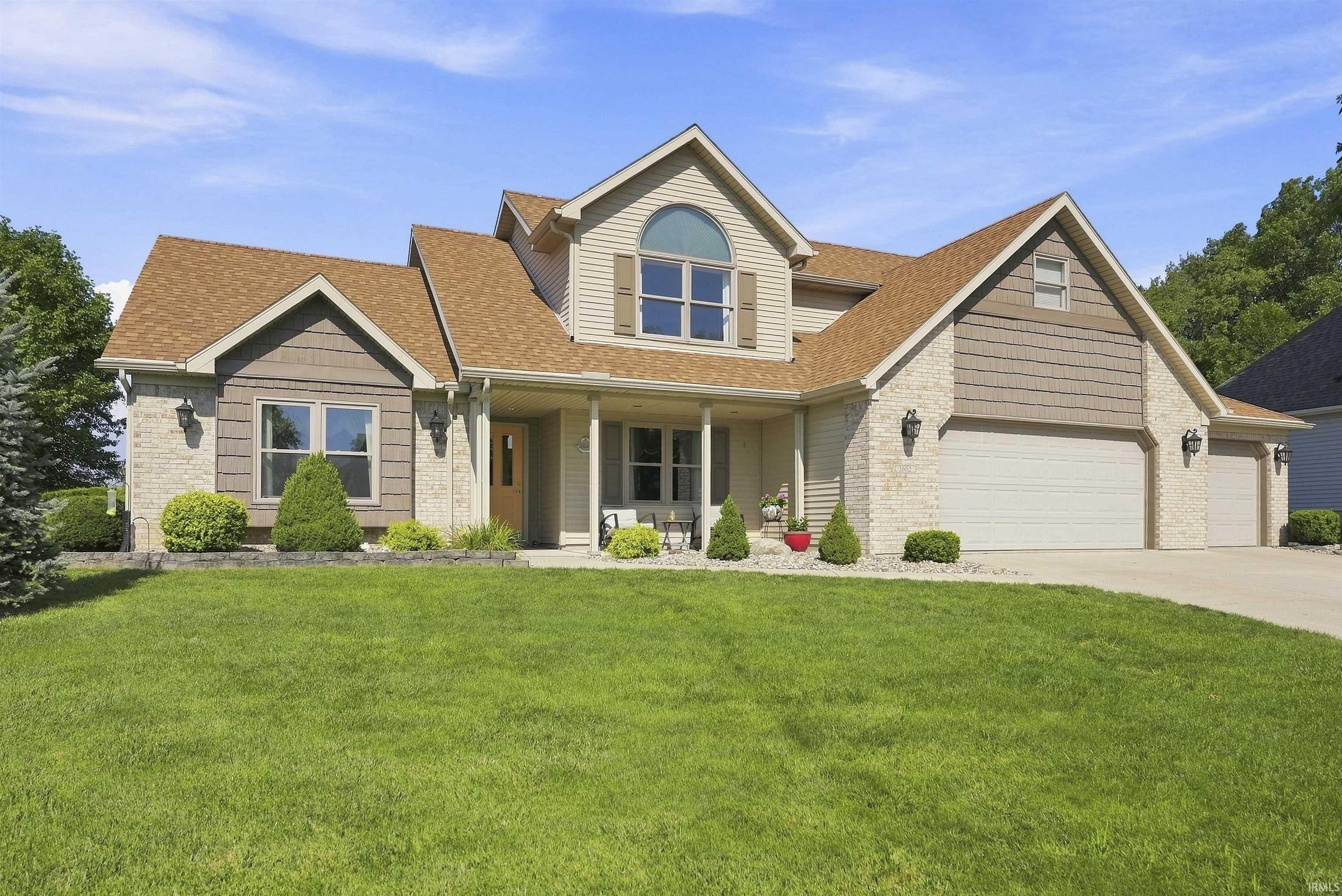 Elegant two-story home featuring a brick and siding exterior with a peaked gable roofline and arched transom windows