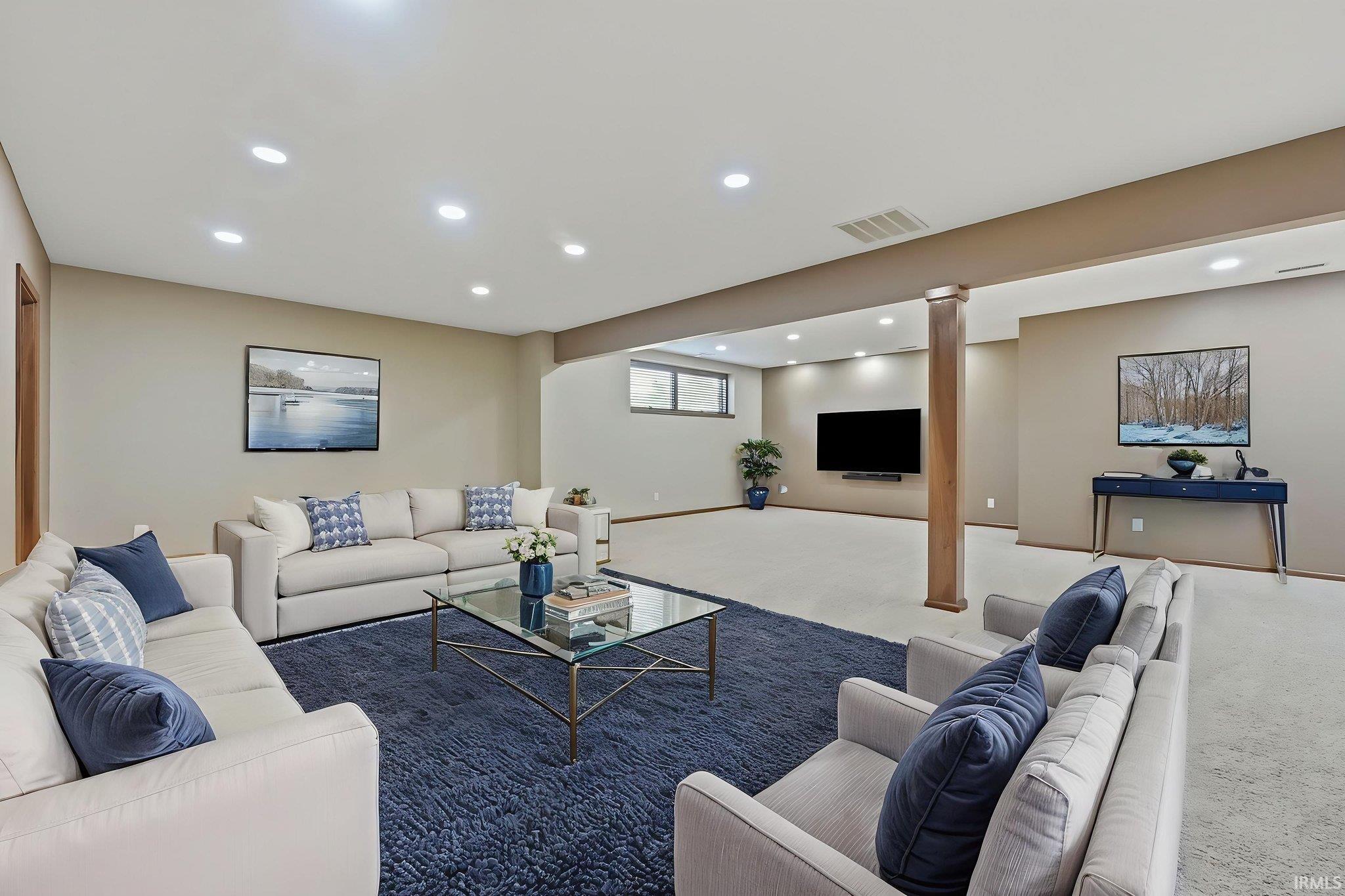 Spacious lower-level living area with recessed lighting, light-toned walls, and wood-finish trim