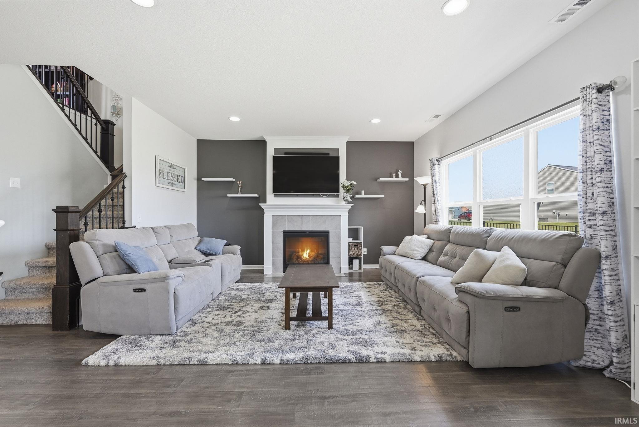 Spacious living area featuring wood-finish flooring, a white mantel fireplace, and recessed lighting