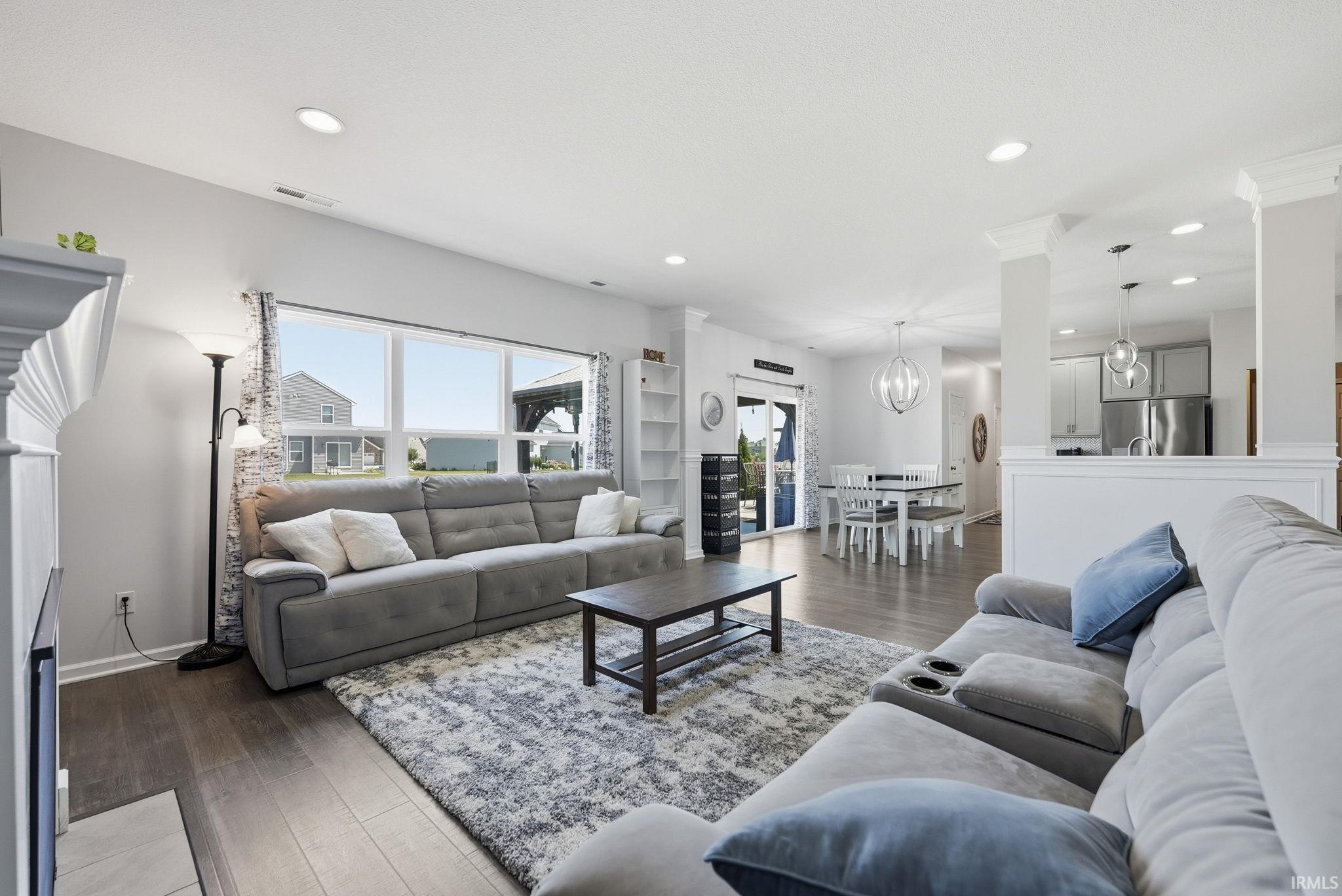 Open-concept living space featuring a gray upholstered sectional sofa, wood-finish flooring throughout, and recessed ceiling lighting