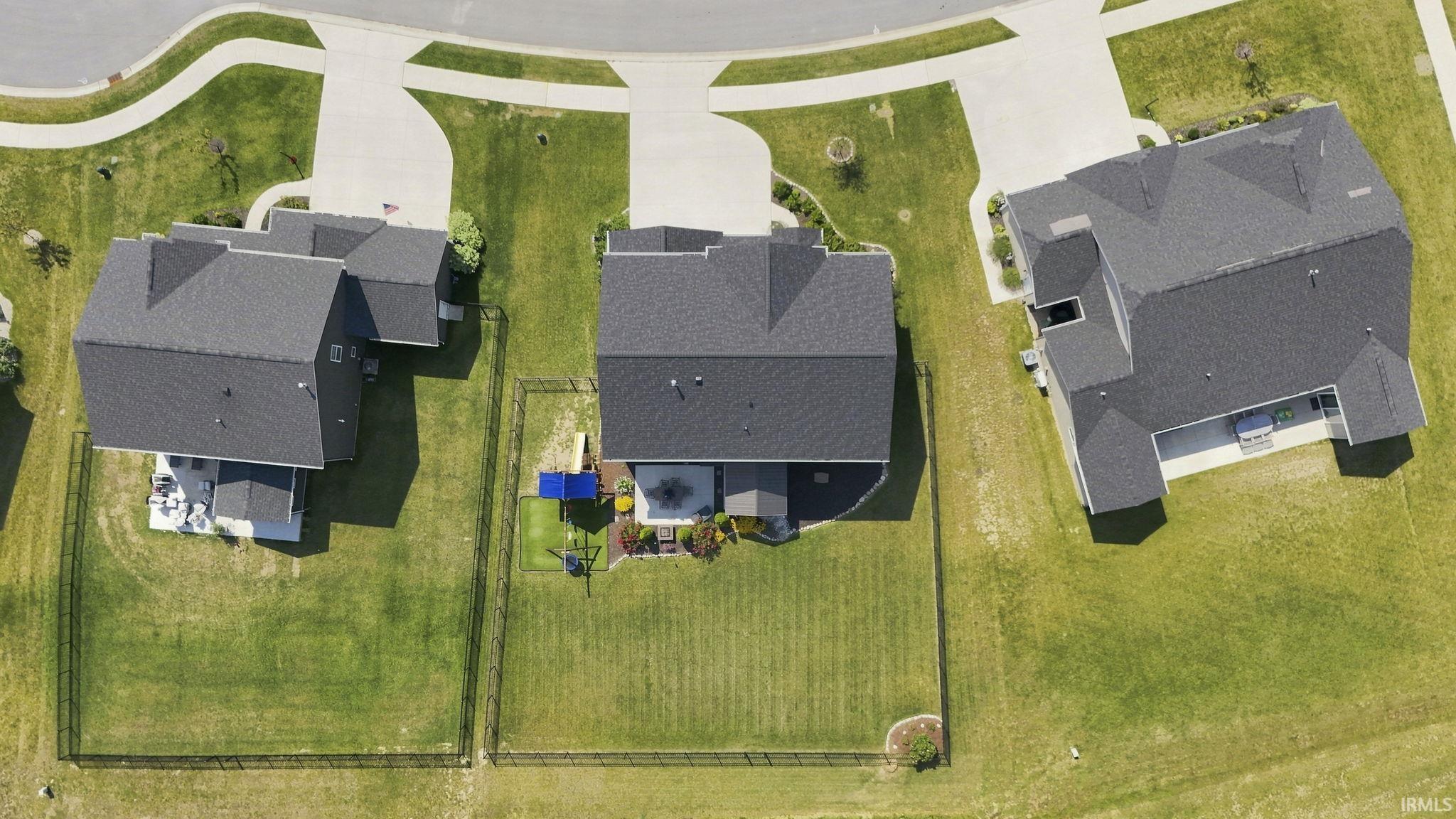 Aerial view showcasing three substantial residential properties situated on expansive, manicured lawns