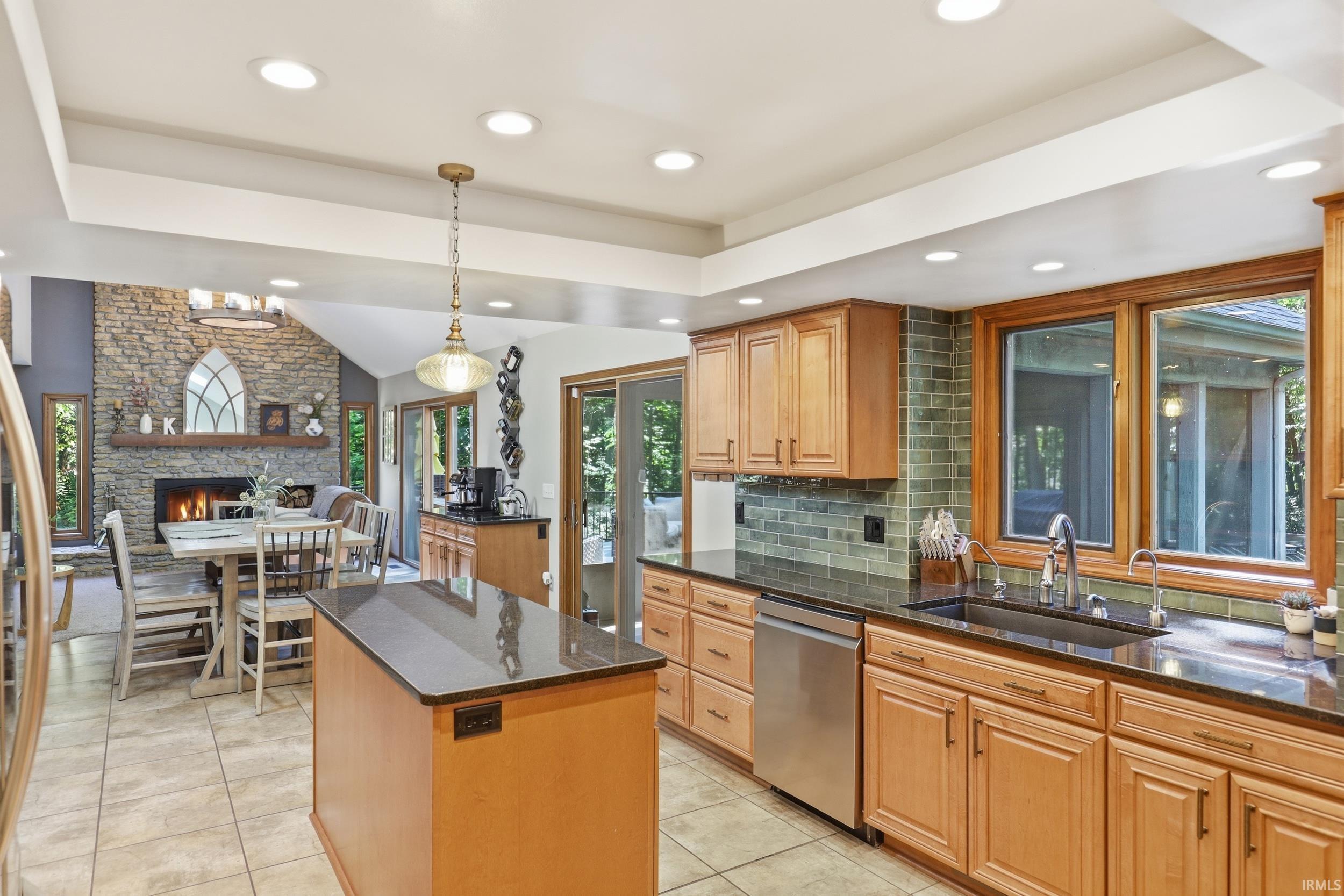 Kitchen featuring light wood cabinetry, dark countertops, and a tiled backsplash