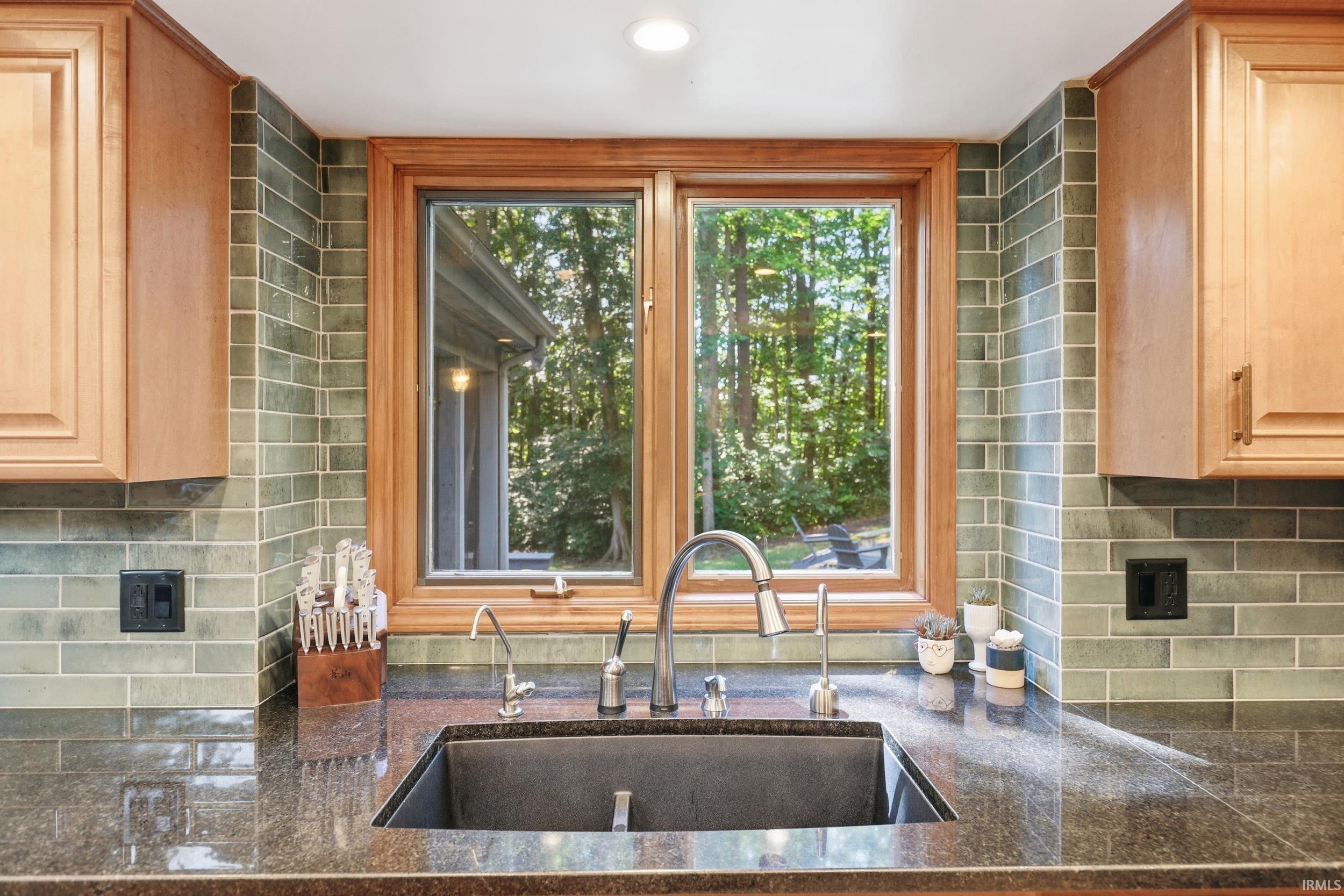 Kitchen window with natural wood trim framing an outdoor landscape