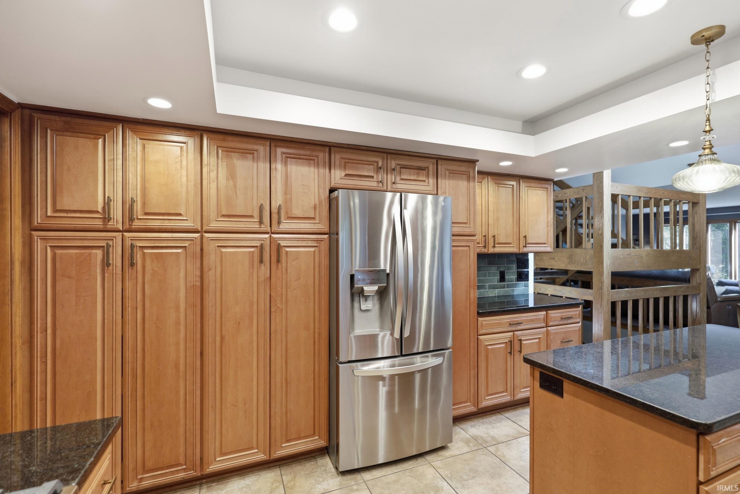 Kitchen with abundant wood cabinetry, recessed lighting, and a stainless steel refrigerator