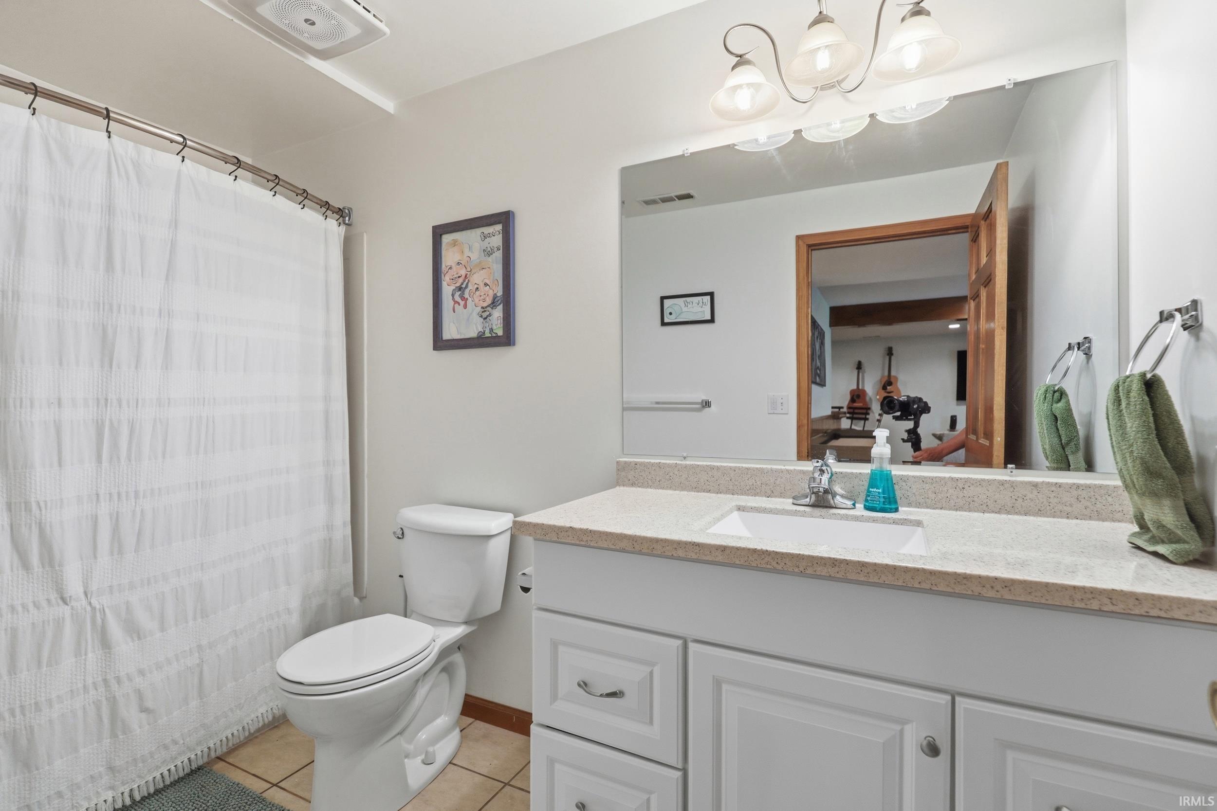 Bathroom featuring a white vanity with a light-colored countertop, an undermount sink, and a wall-mounted mirror