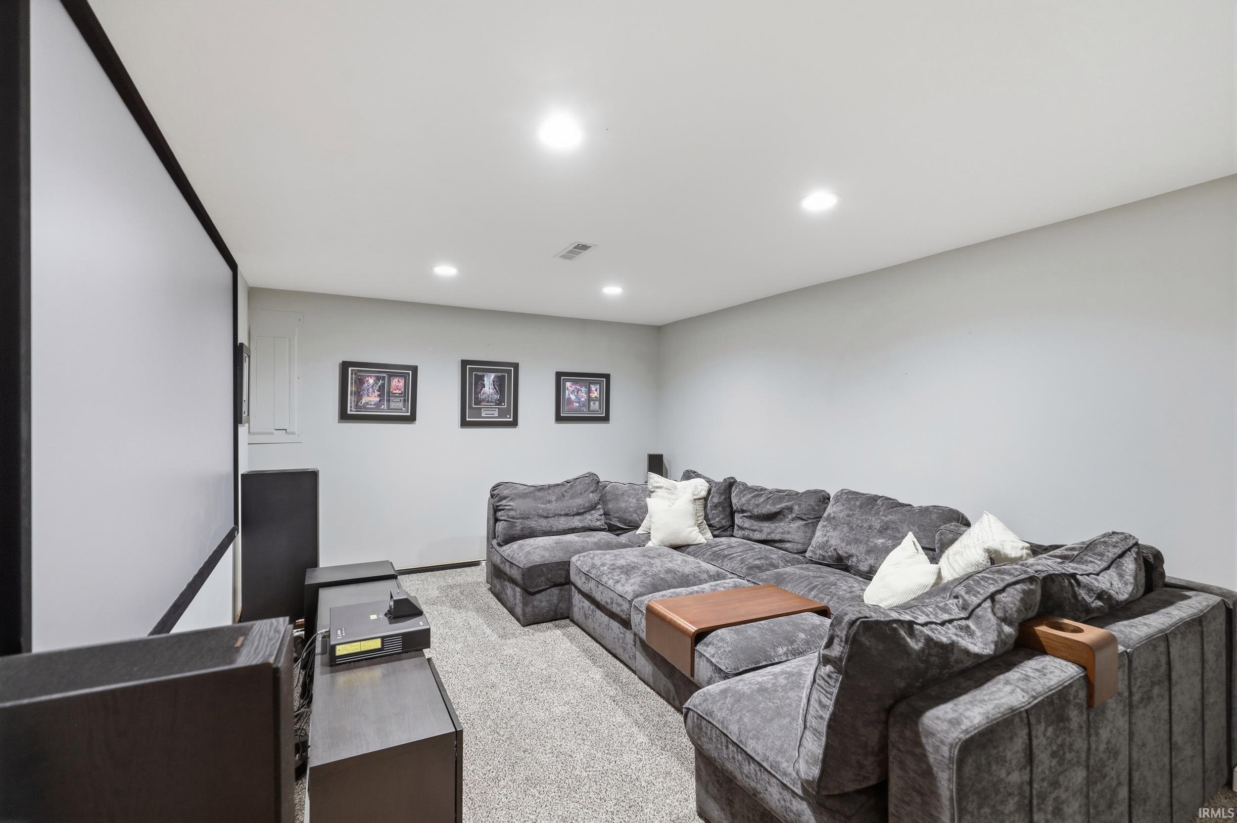 Dedicated media room featuring a large projection screen, recessed lighting, and light grey walls