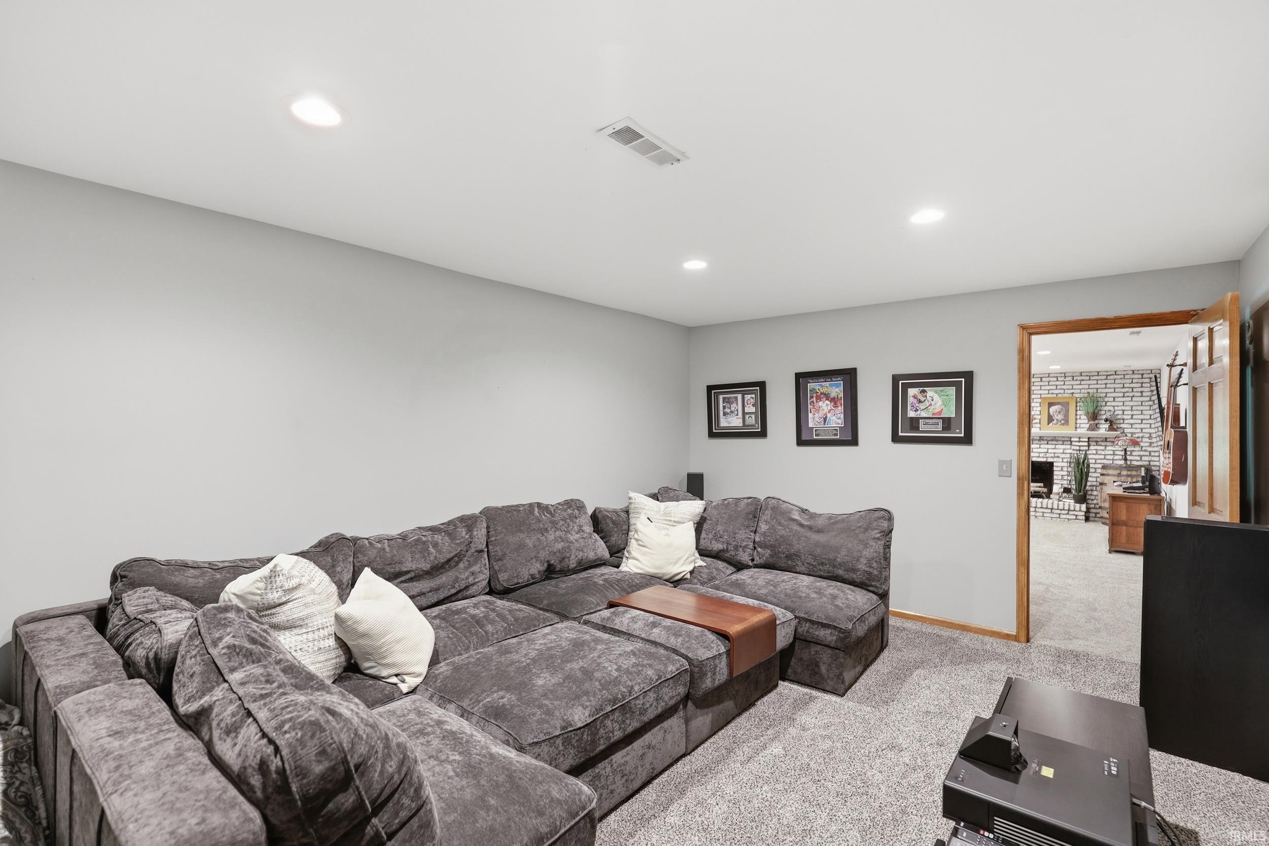 Carpeted recreation room featuring recessed lighting and a doorway with wood trim