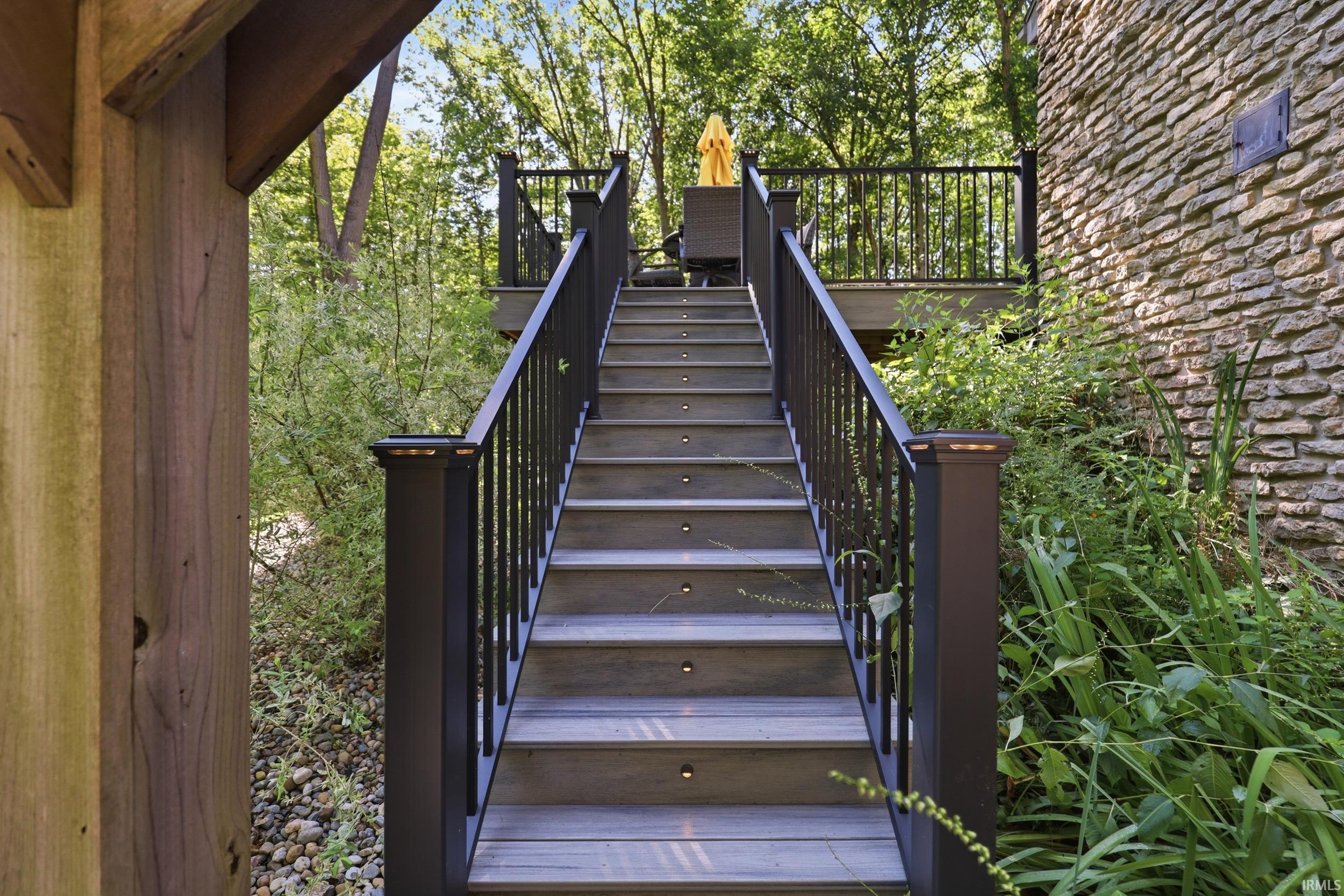 Exterior deck stairs featuring composite decking, integrated step lighting, and black metal railings