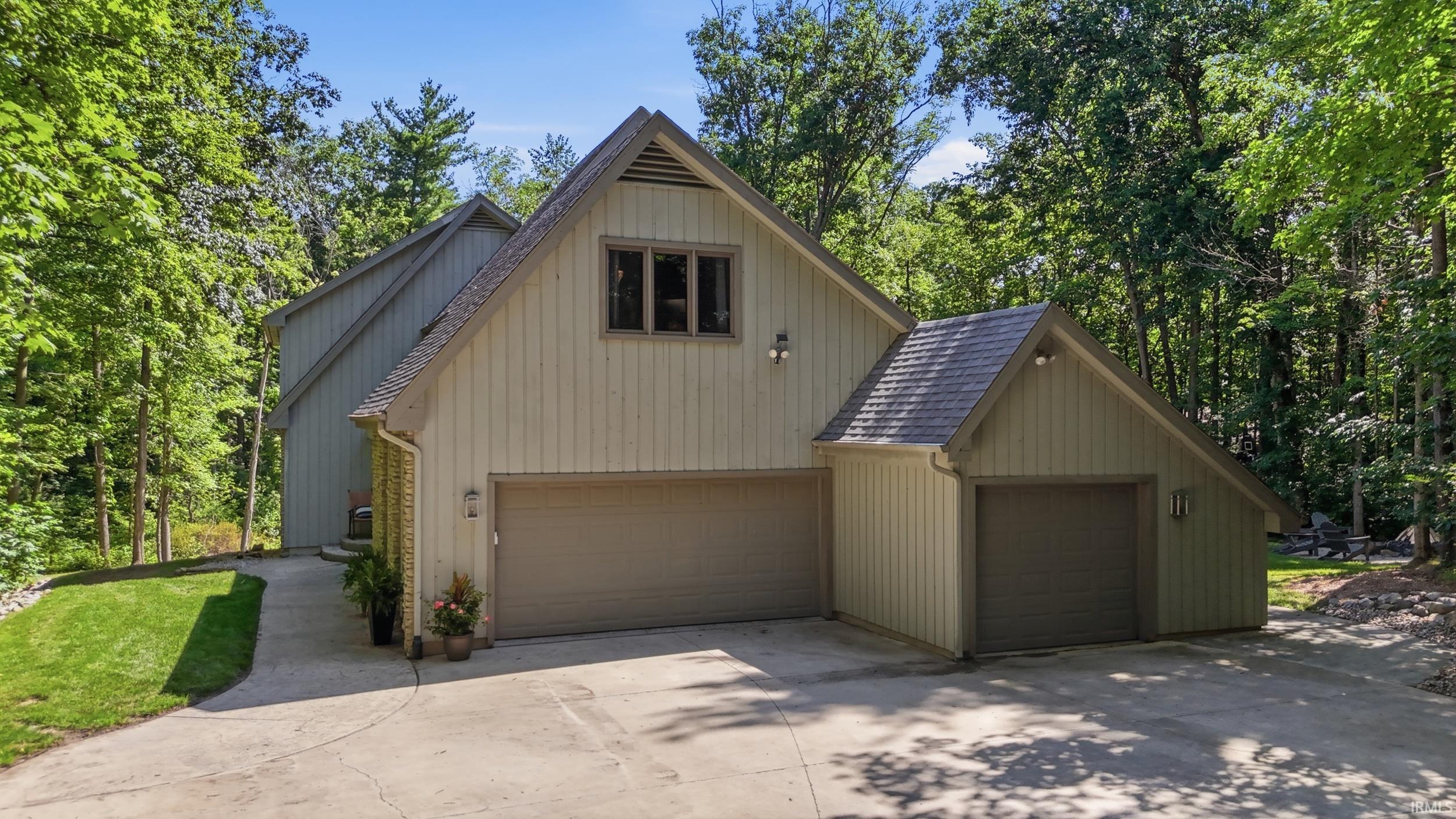 Expansive concrete driveway leading to a multi-car garage with two distinct garage doors
