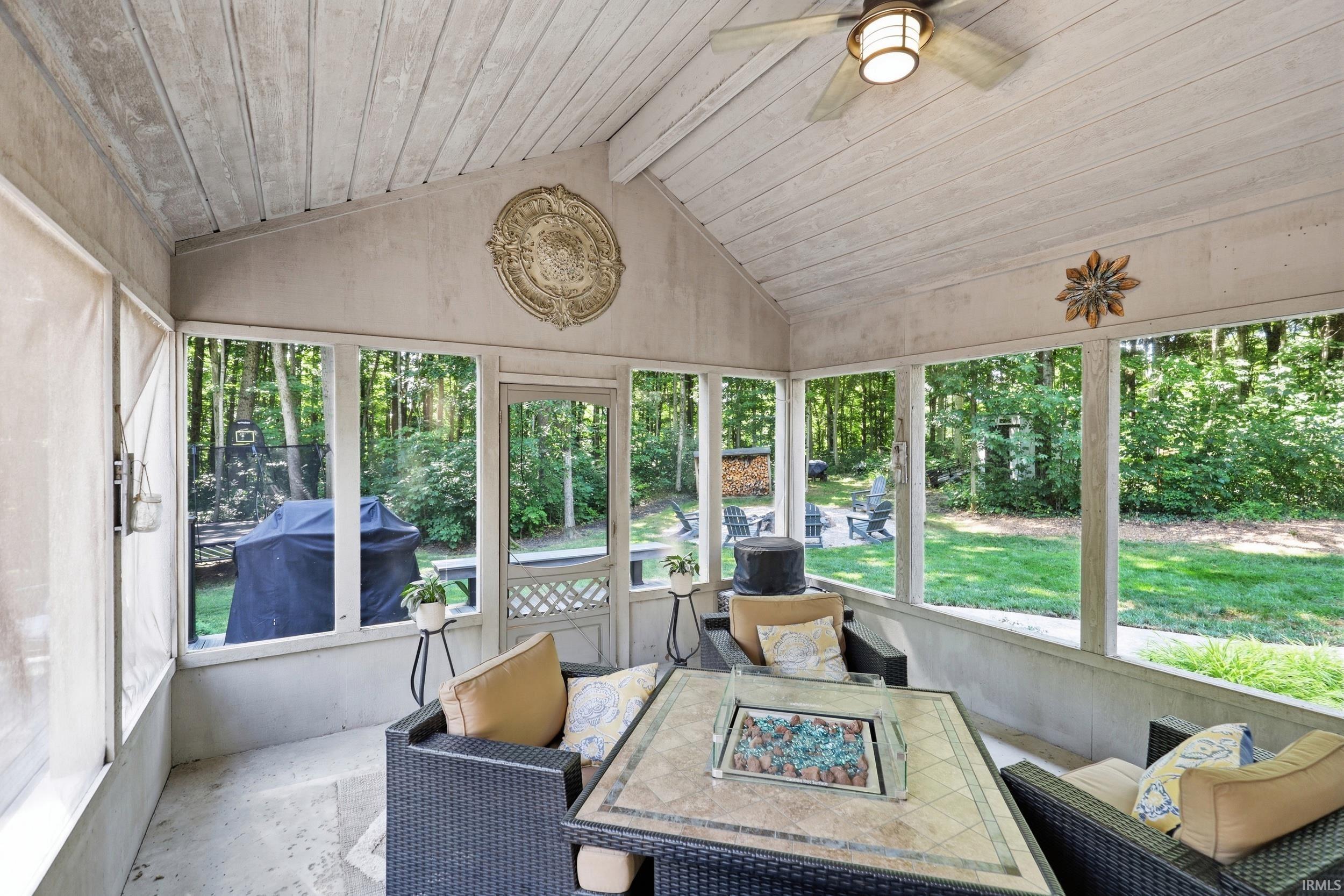Screened porch featuring a vaulted wood-finish ceiling, ceiling fan, and large windows overlooking the backyard