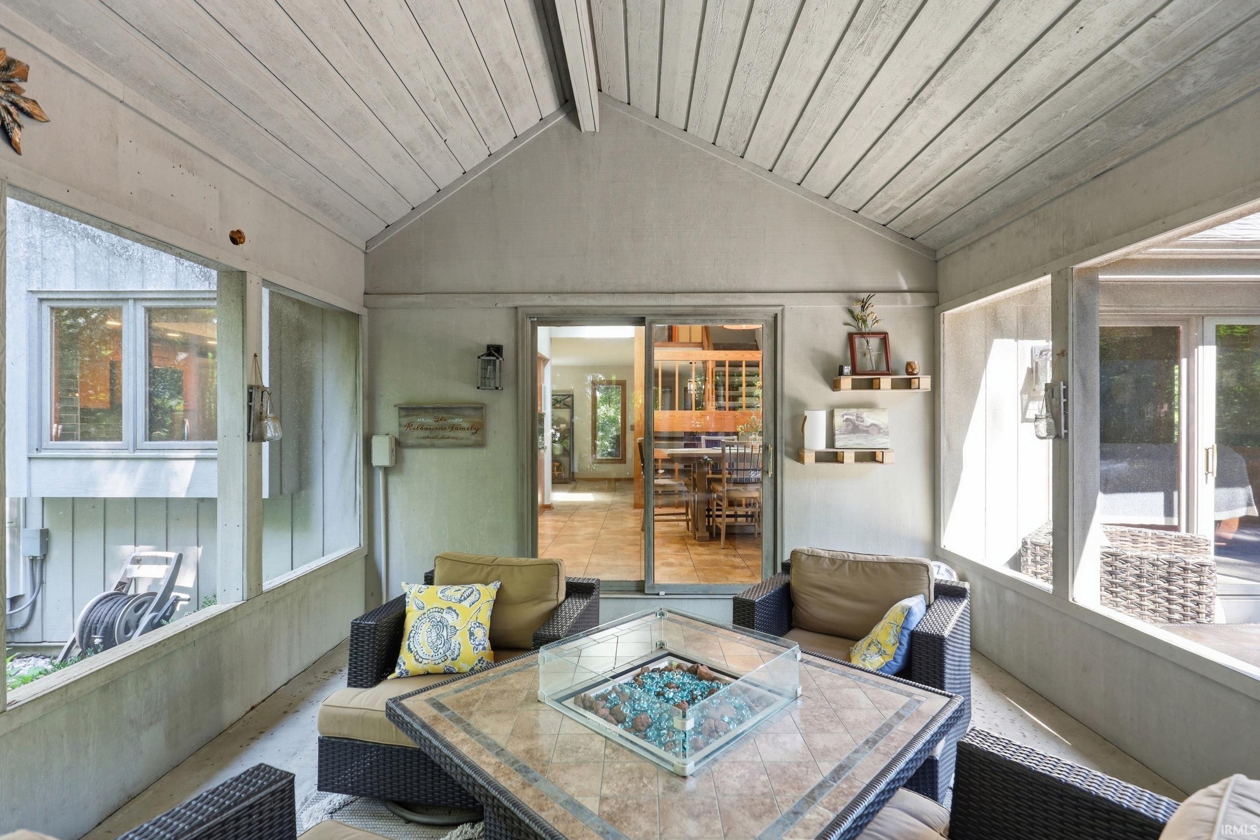 Screened porch featuring a vaulted wood-plank ceiling, tiled flooring, and sliding glass doors