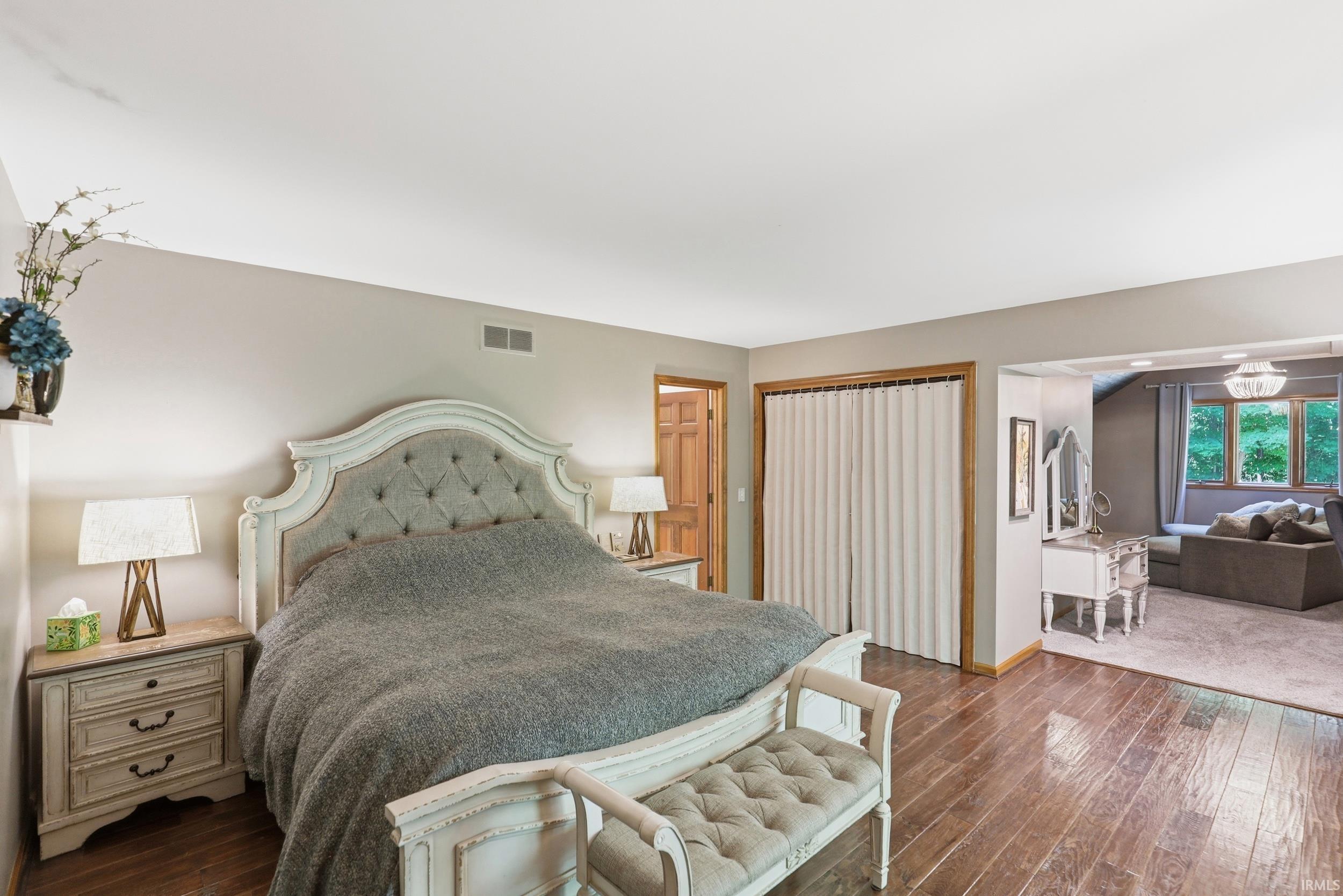 Spacious room featuring wood-finish flooring, light grey walls, and a recessed sitting area with a window