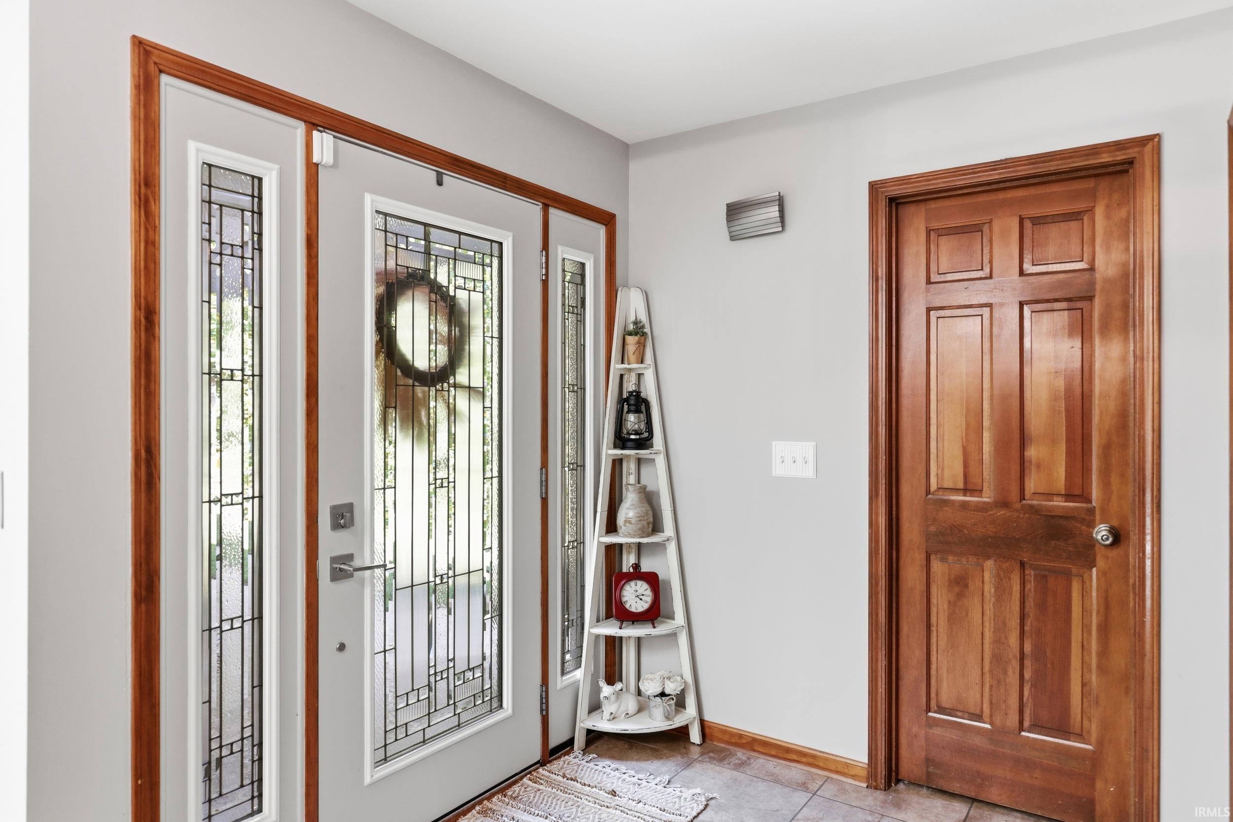 Entryway featuring a white door with decorative glass inserts, flanked by matching sidelights, all framed with natural wood trim