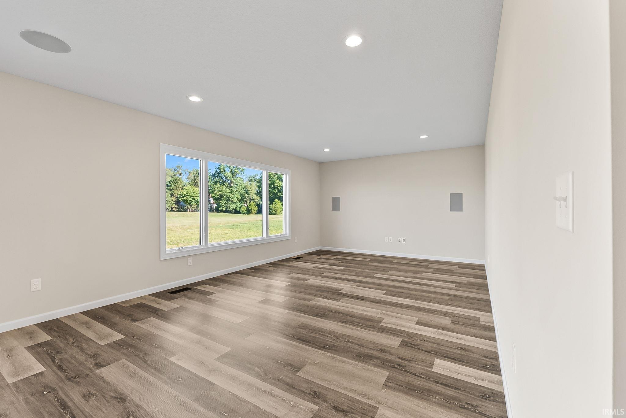 Spacious interior room featuring wood-finish flooring, recessed lighting, and a large multi-pane window