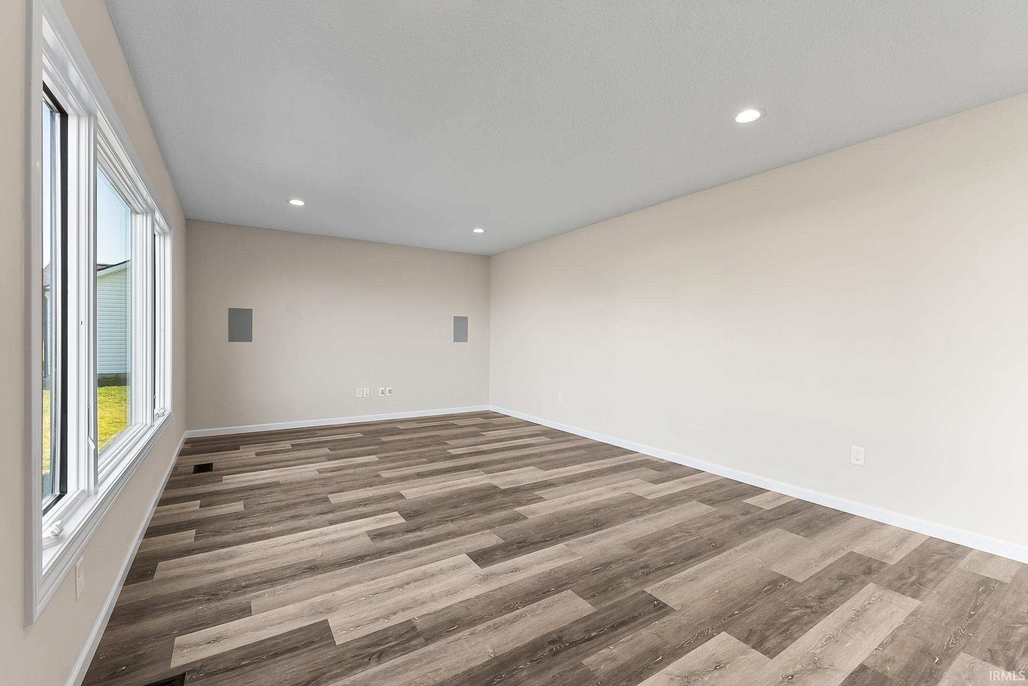 Spacious room featuring wood-finish flooring, recessed lighting, and a large multi-pane window