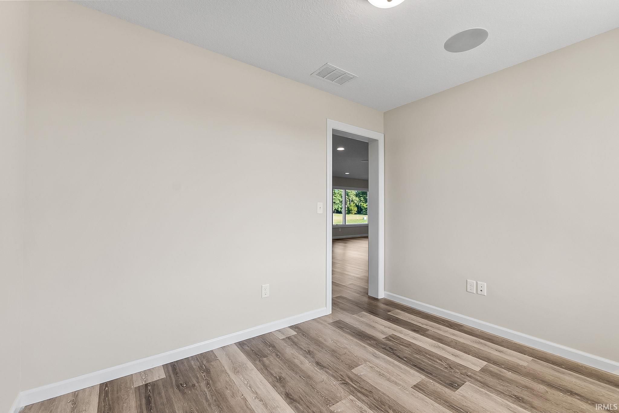 Room featuring wood-finish flooring, light-toned wall paint, white trim, and a ceiling-mounted light fixture