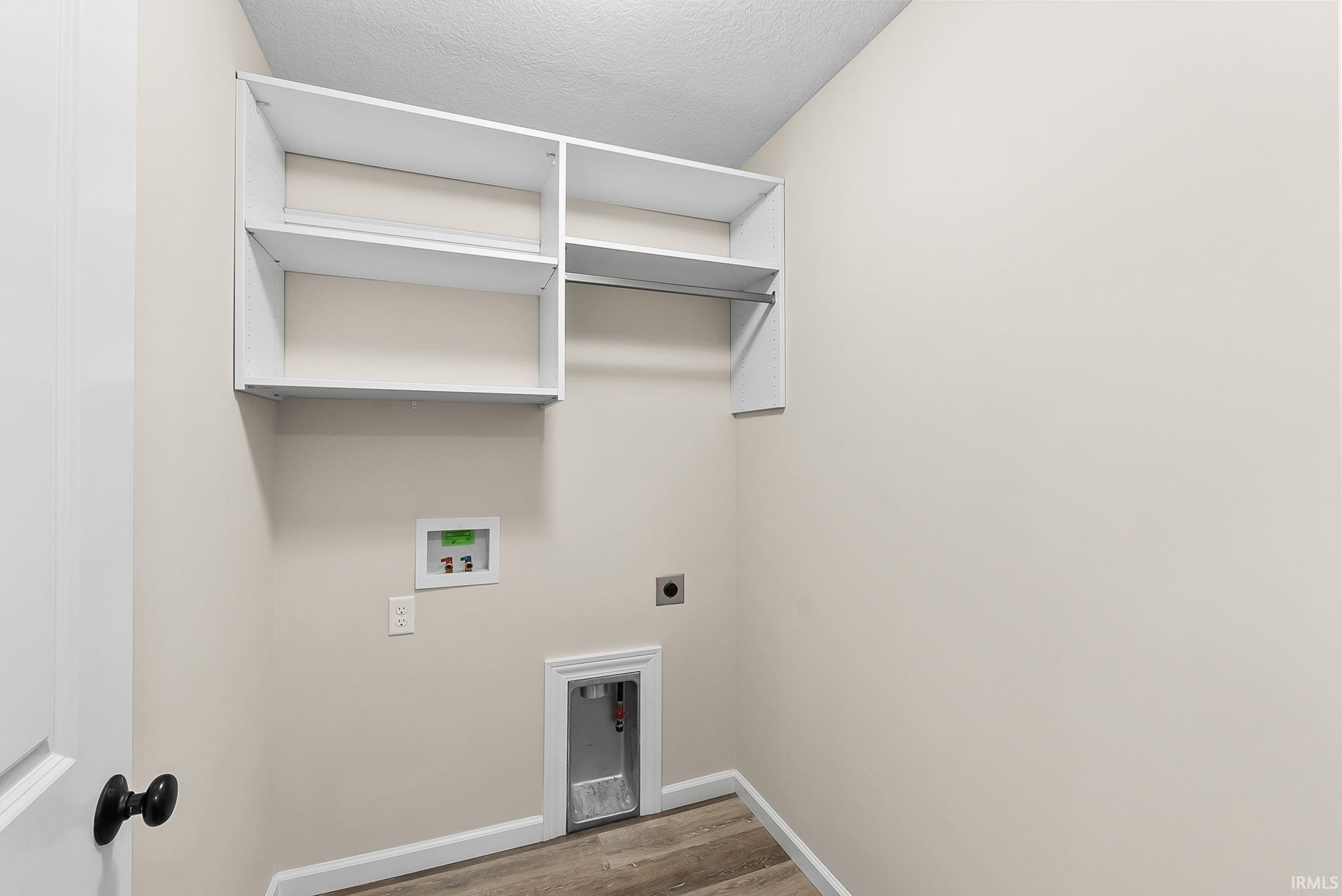 Utility area featuring built-in white shelving, a clothes hanging rod, wood-finish flooring, and light neutral wall paint