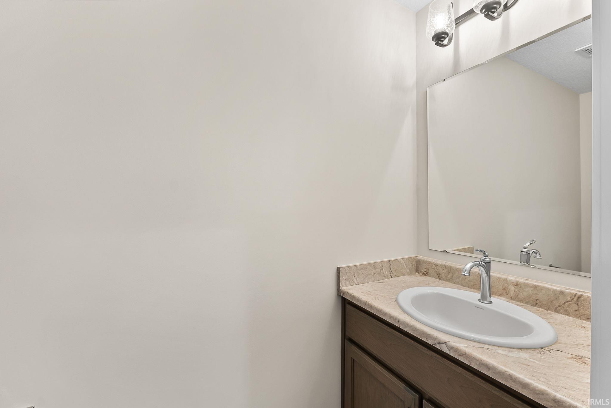 Vanity with an oval undermount sink, stone countertop, brushed nickel faucet, and a large wall-mounted mirror