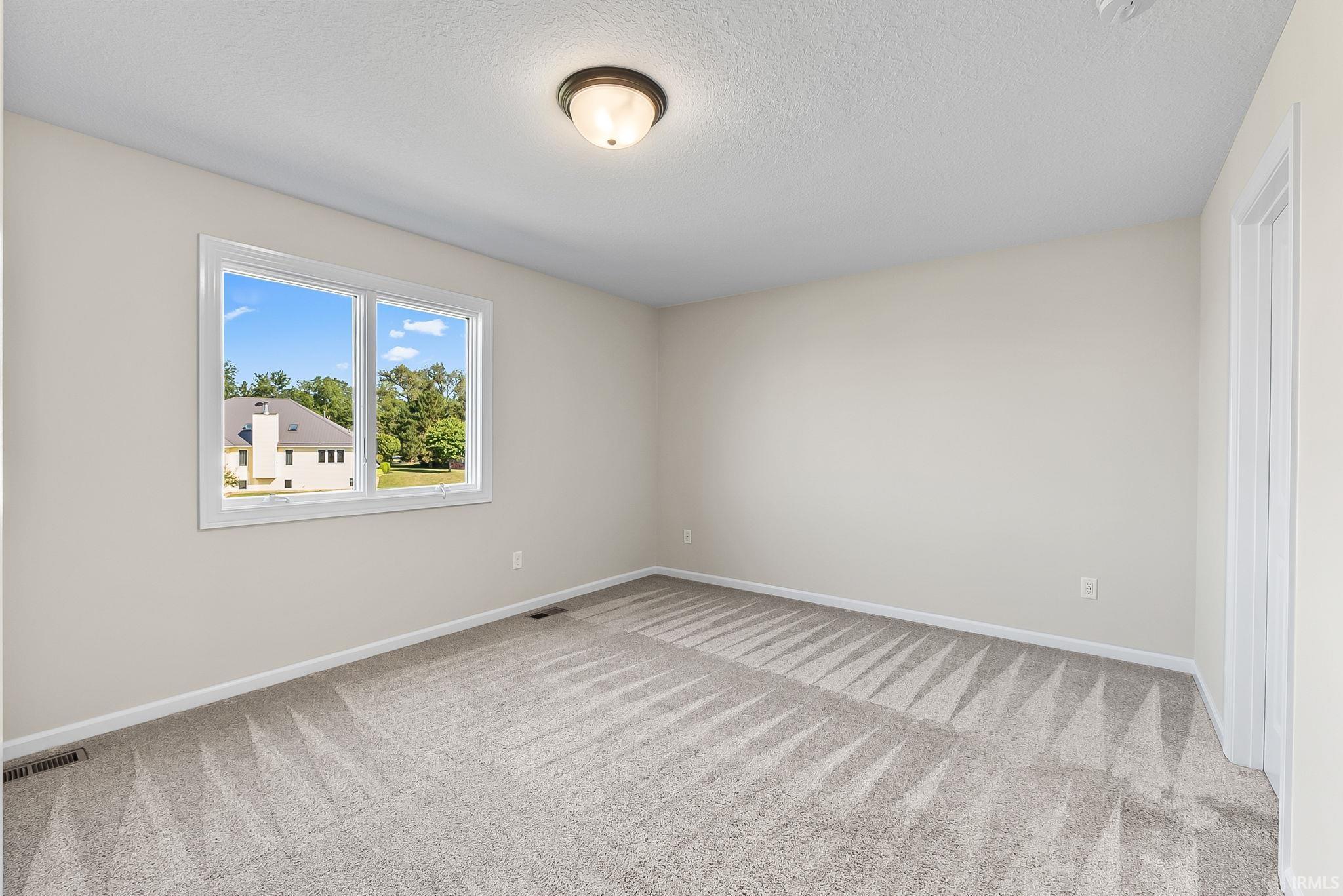 Neutral tone wall paint, light gray patterned carpet, white trim, and a flush mount ceiling light fixture