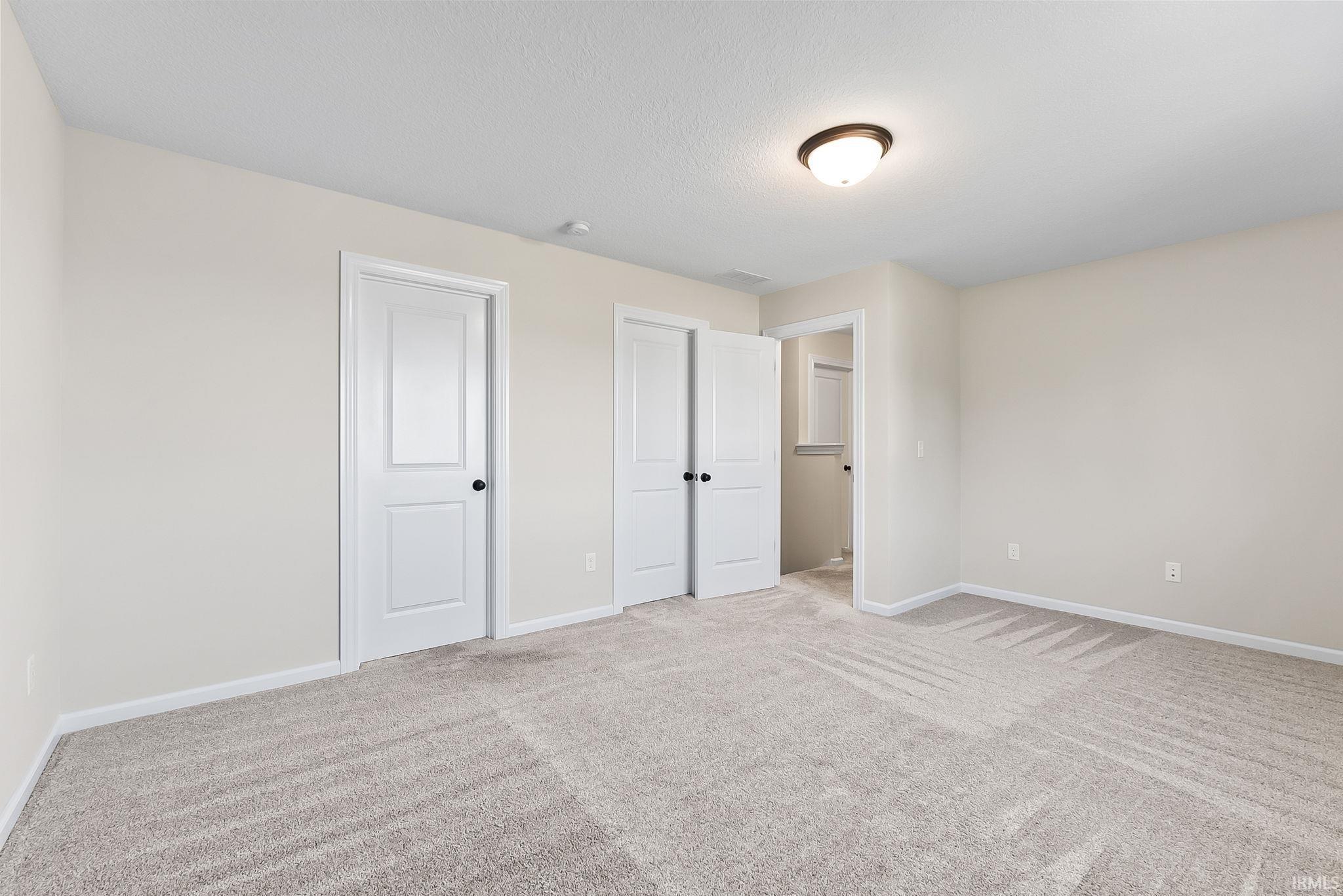 Carpeted room with neutral wall tones and a flush-mount ceiling light