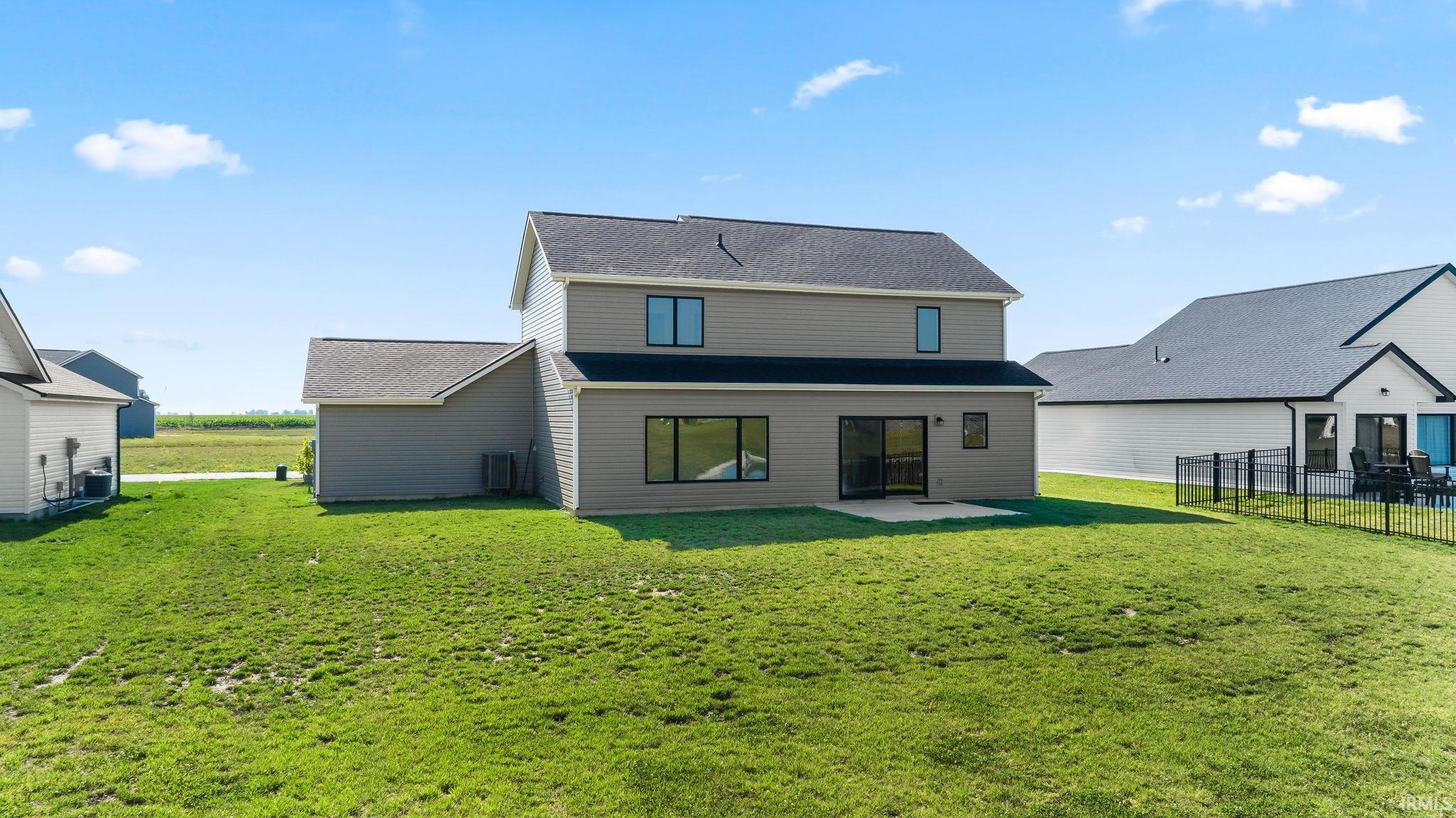 Rear exterior featuring a concrete patio, sliding glass door access, multiple windows, and a gray siding finish