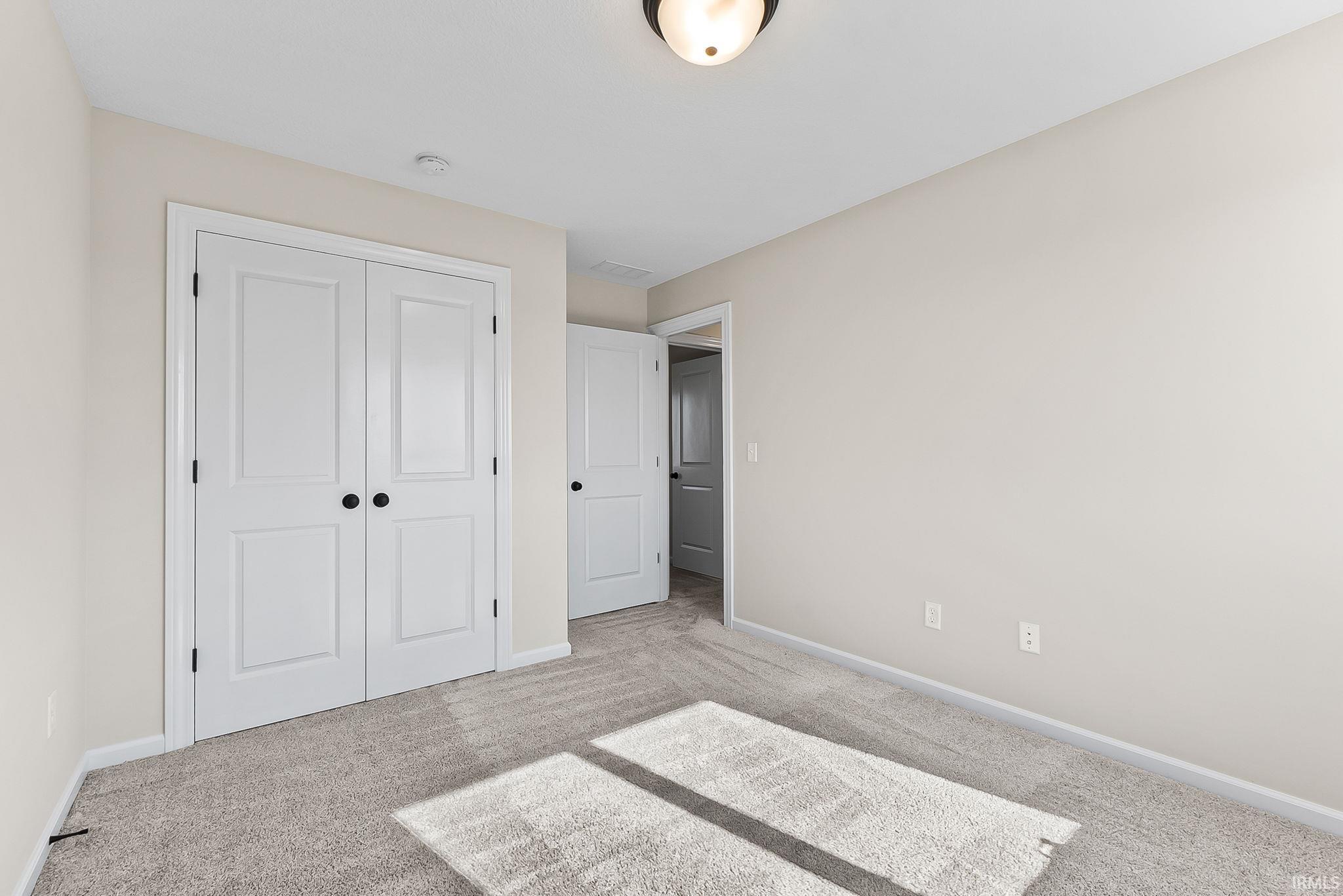 Spacious bedroom featuring neutral wall finishes, plush carpeting, and abundant natural light from recessed ceiling fixtures