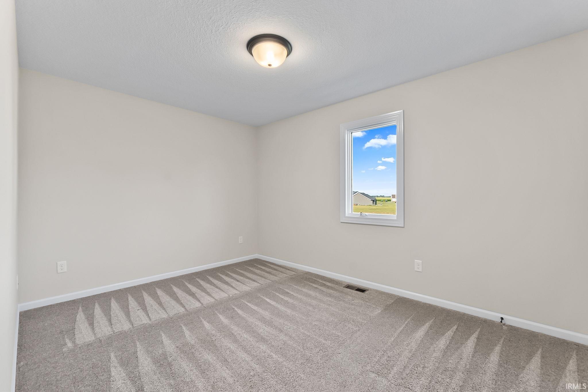 Bedroom featuring light gray carpet with a patterned texture, neutral wall paint, white trim, and a flush mount ceiling light