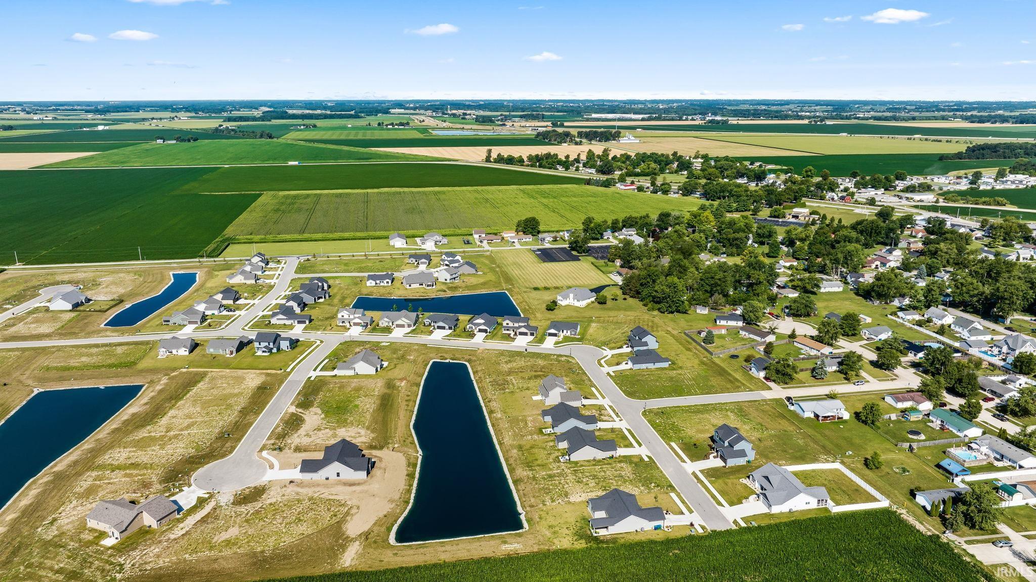 Aerial view of this residential community featuring multiple newly constructed homes situated on spacious lots with private retention ponds, mature landscaping, and open green spaces