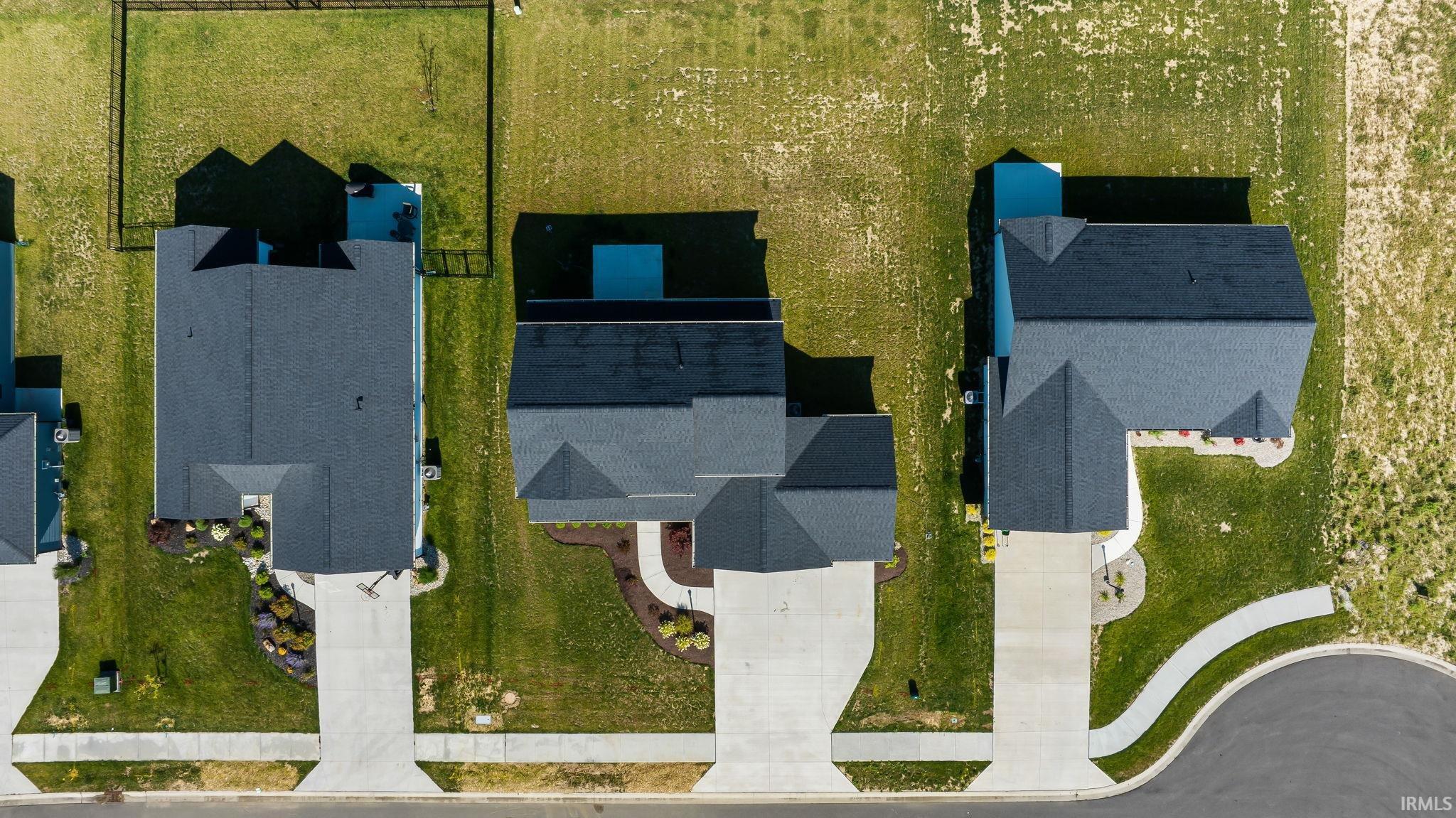Overhead view highlighting three residential properties with gray shingled roofs and concrete driveways