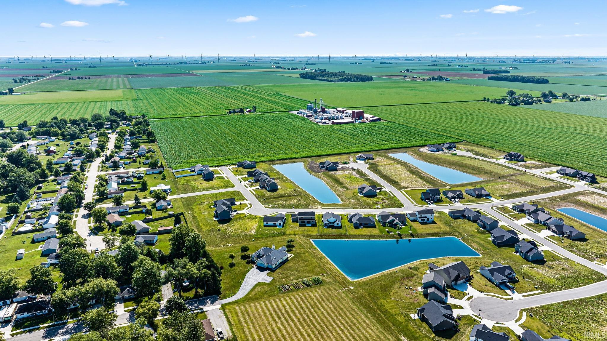 Aerial perspective showcasing a residential development with multiple homes and serene water features