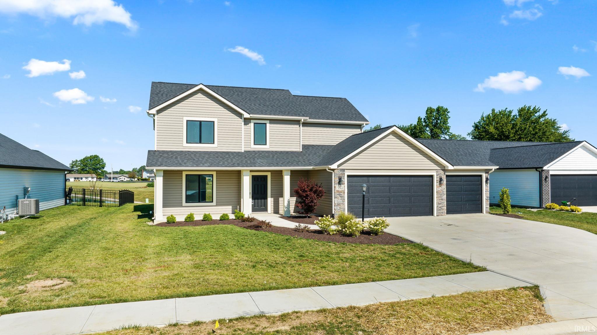Contemporary residence featuring a two-story design with light-toned siding, dark roofing, and a prominent attached three-car garage