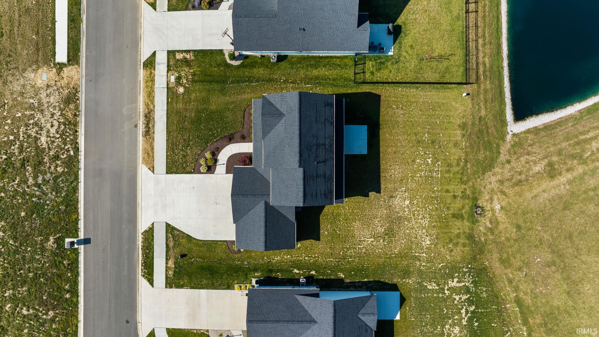 Aerial view of a residential property featuring a gray shingle roof and concrete driveway