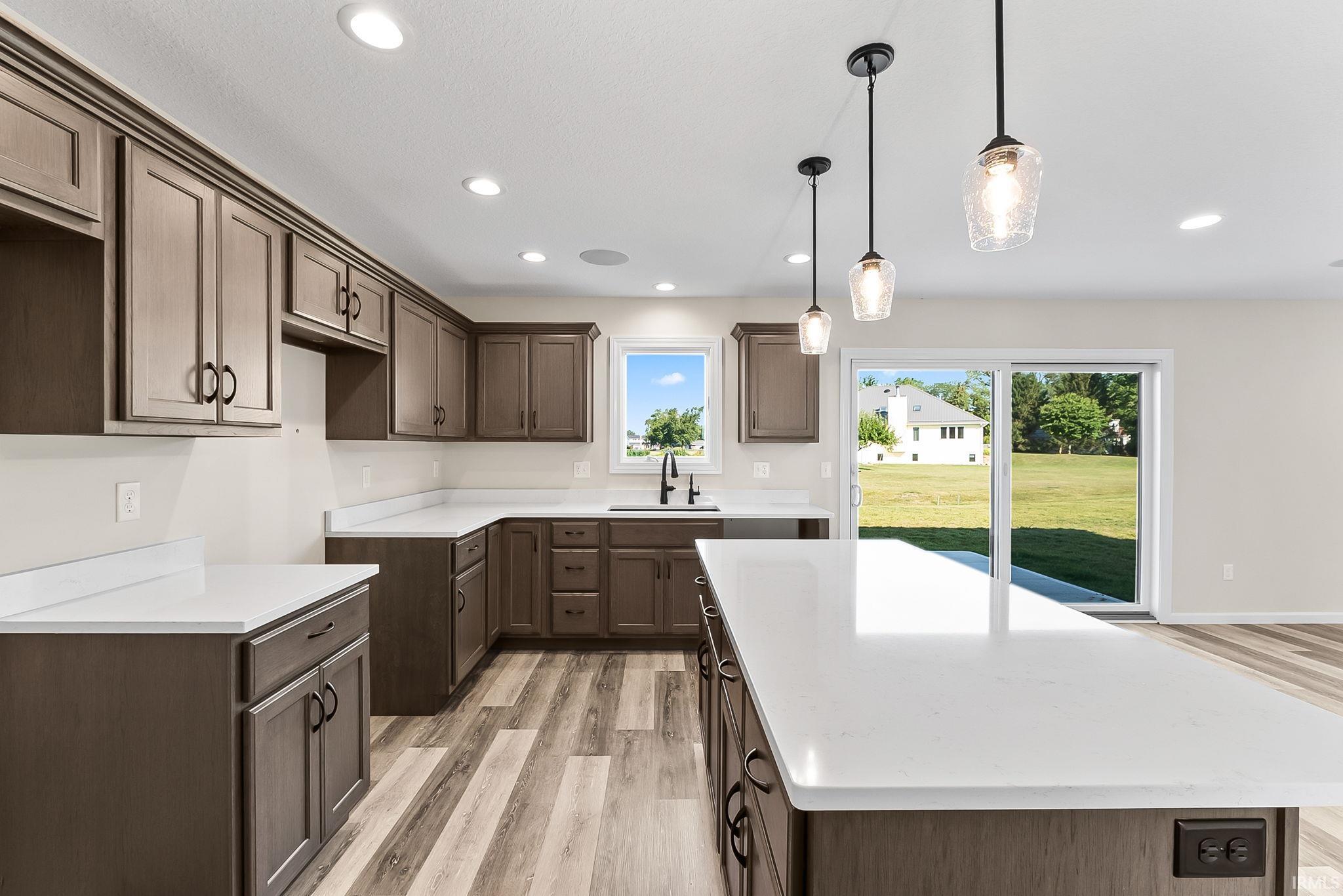 Stunning chef's kitchen featuring rich cabinetry with brushed metal hardware, white quartz countertops, and a large waterfall-edge island