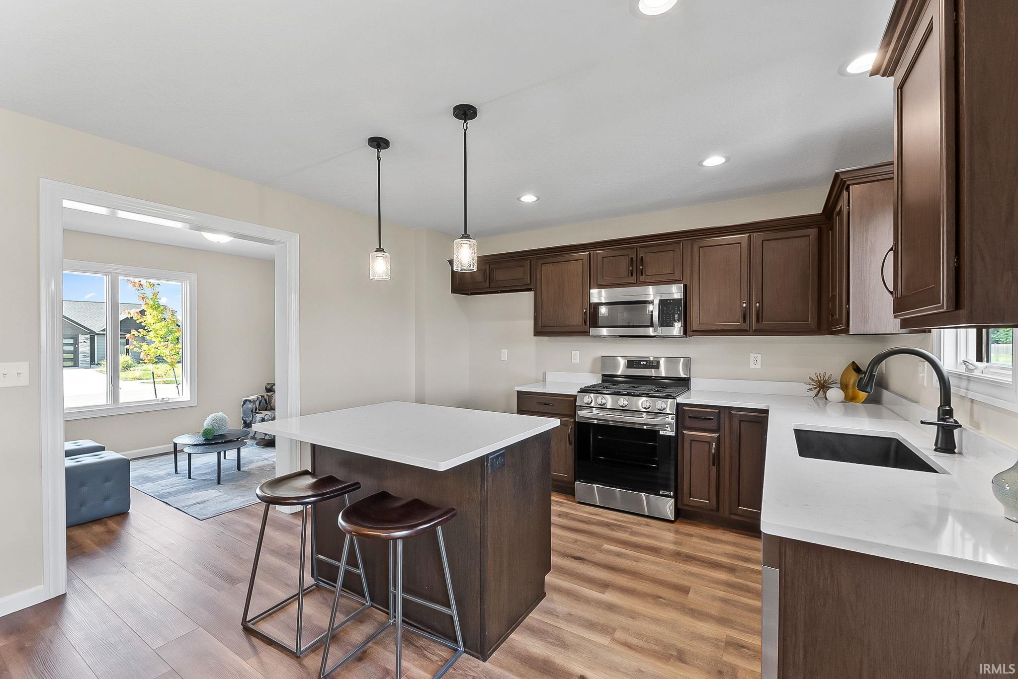 Modern kitchen featuring dark wood-finish cabinetry, stainless steel appliances, and white countertops