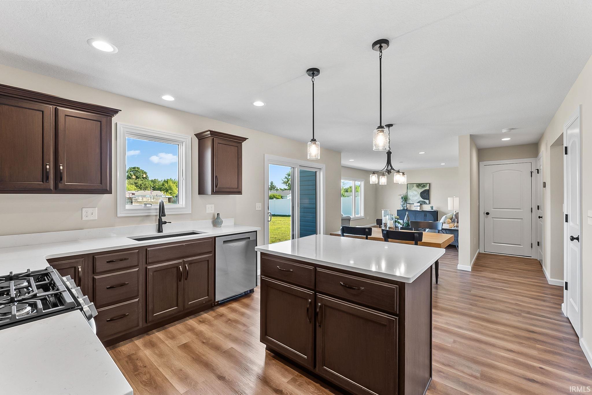 Kitchen featuring dark wood cabinetry, white countertops, stainless steel appliances, and wood-finish flooring