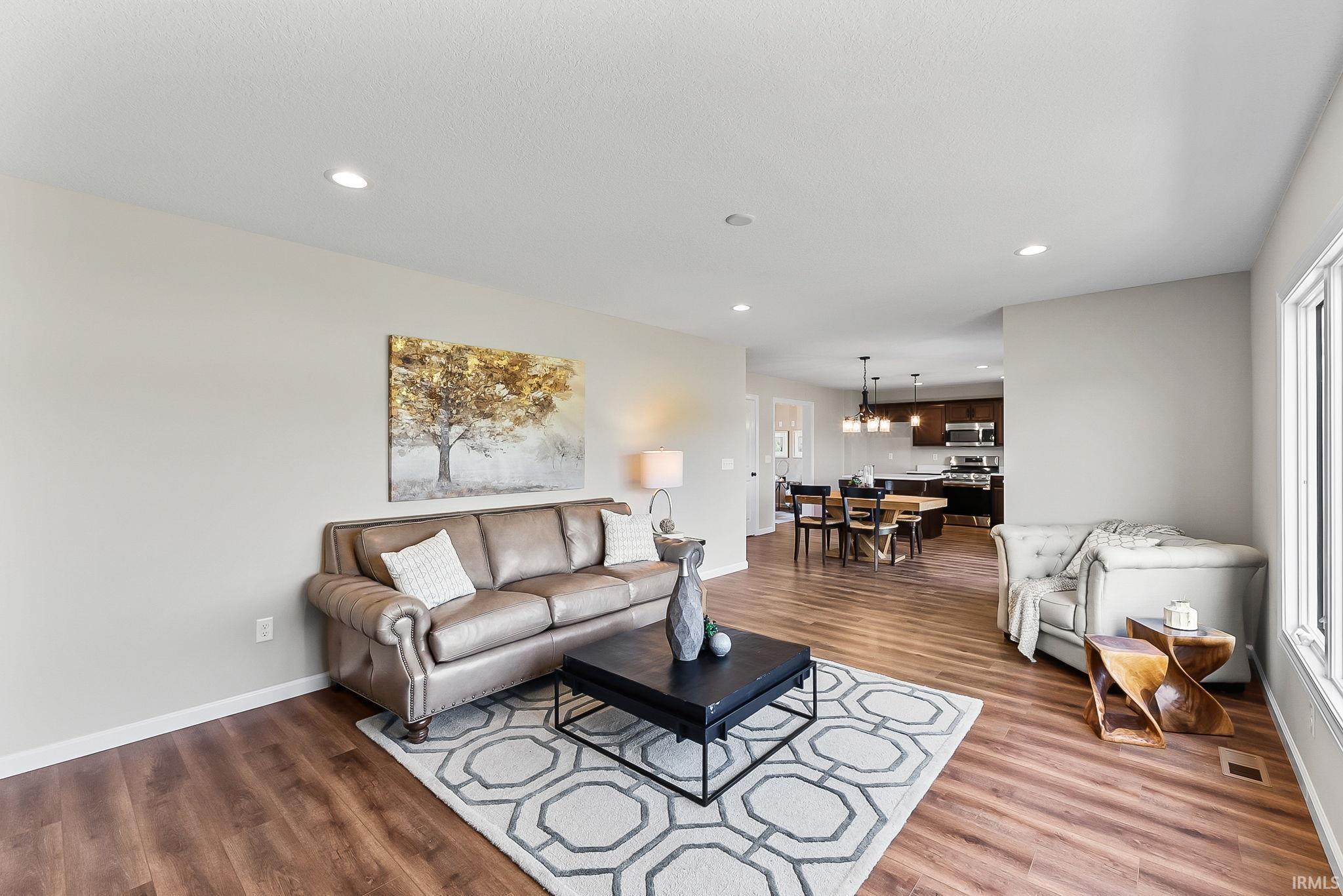 Expansive living area featuring wood-finish flooring, recessed lighting, and a neutral color palette