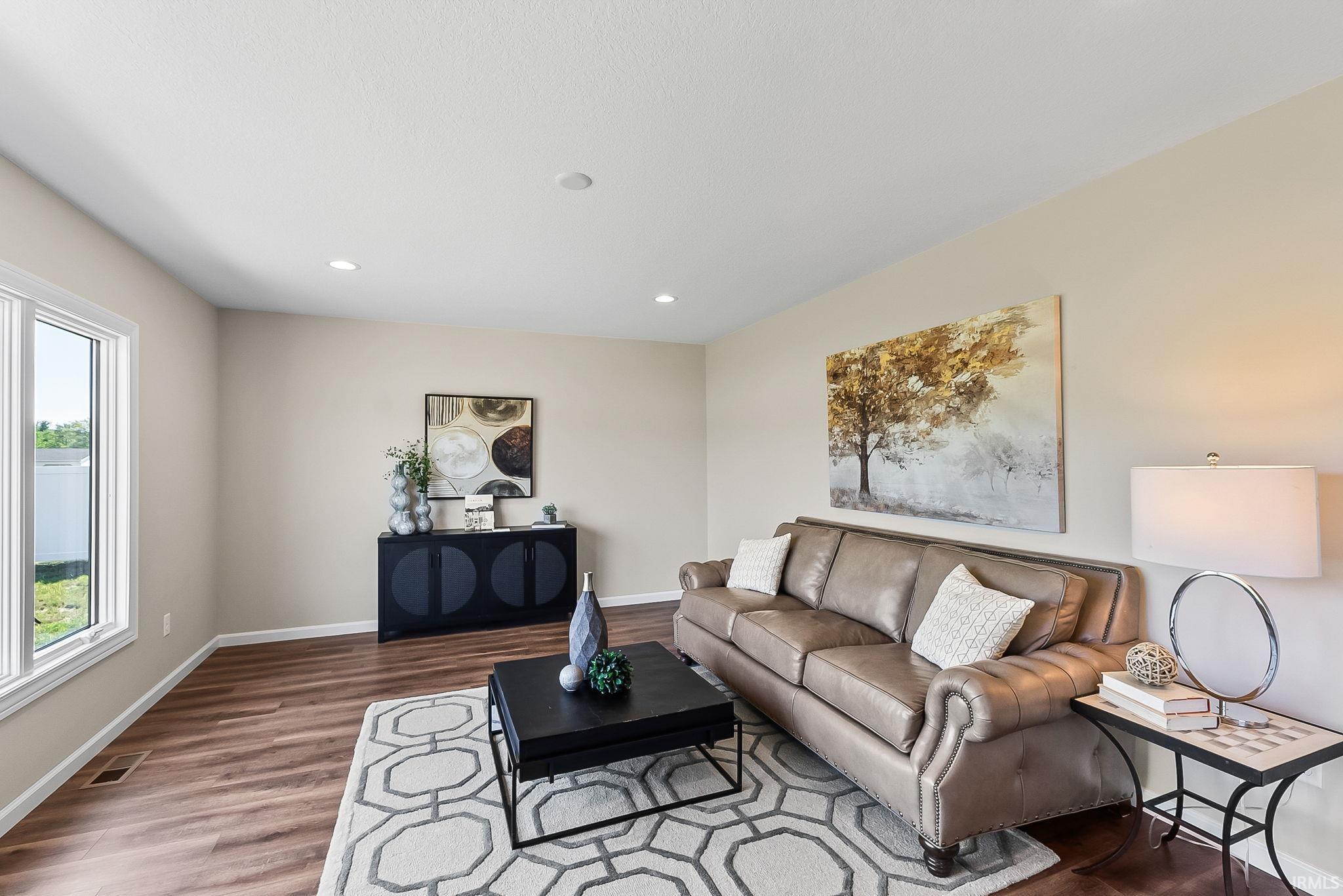 Spacious living area featuring wood-finish flooring, recessed lighting, and large white-framed windows