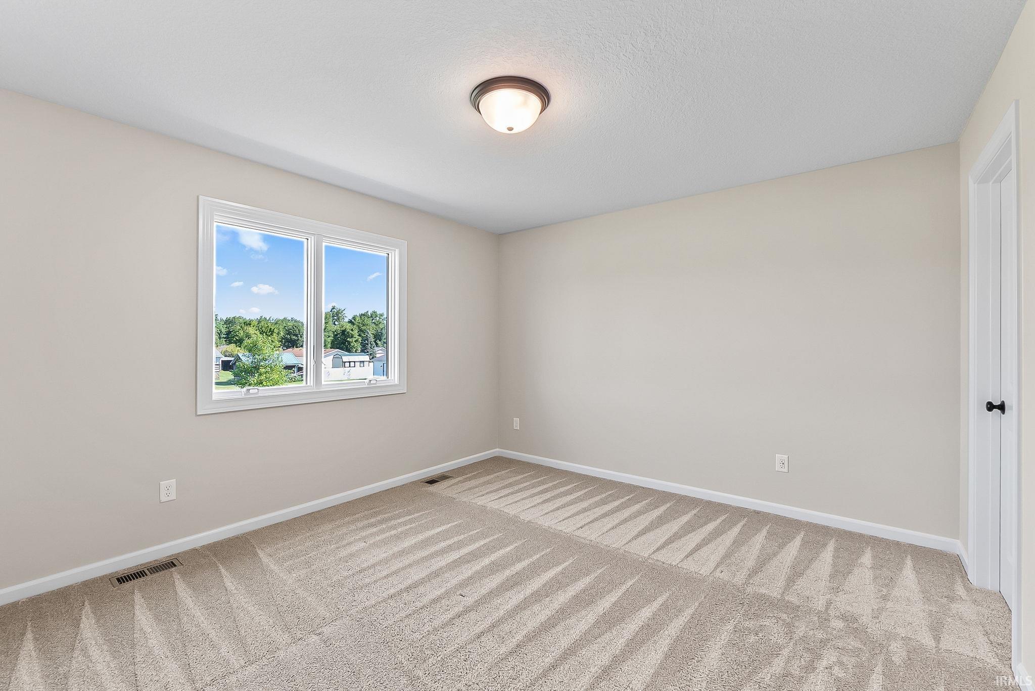 Carpeted room with a double-pane window, white trim, light-colored walls, and a semi-flush mount ceiling light