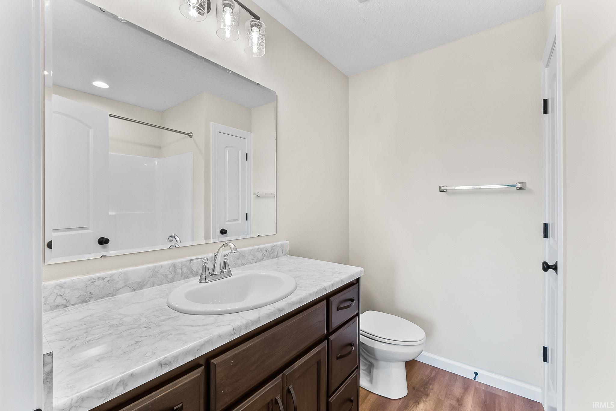 Bathroom featuring a brown-stained vanity with a white countertop, an undermount sink with a chrome faucet, and a large wall mirror