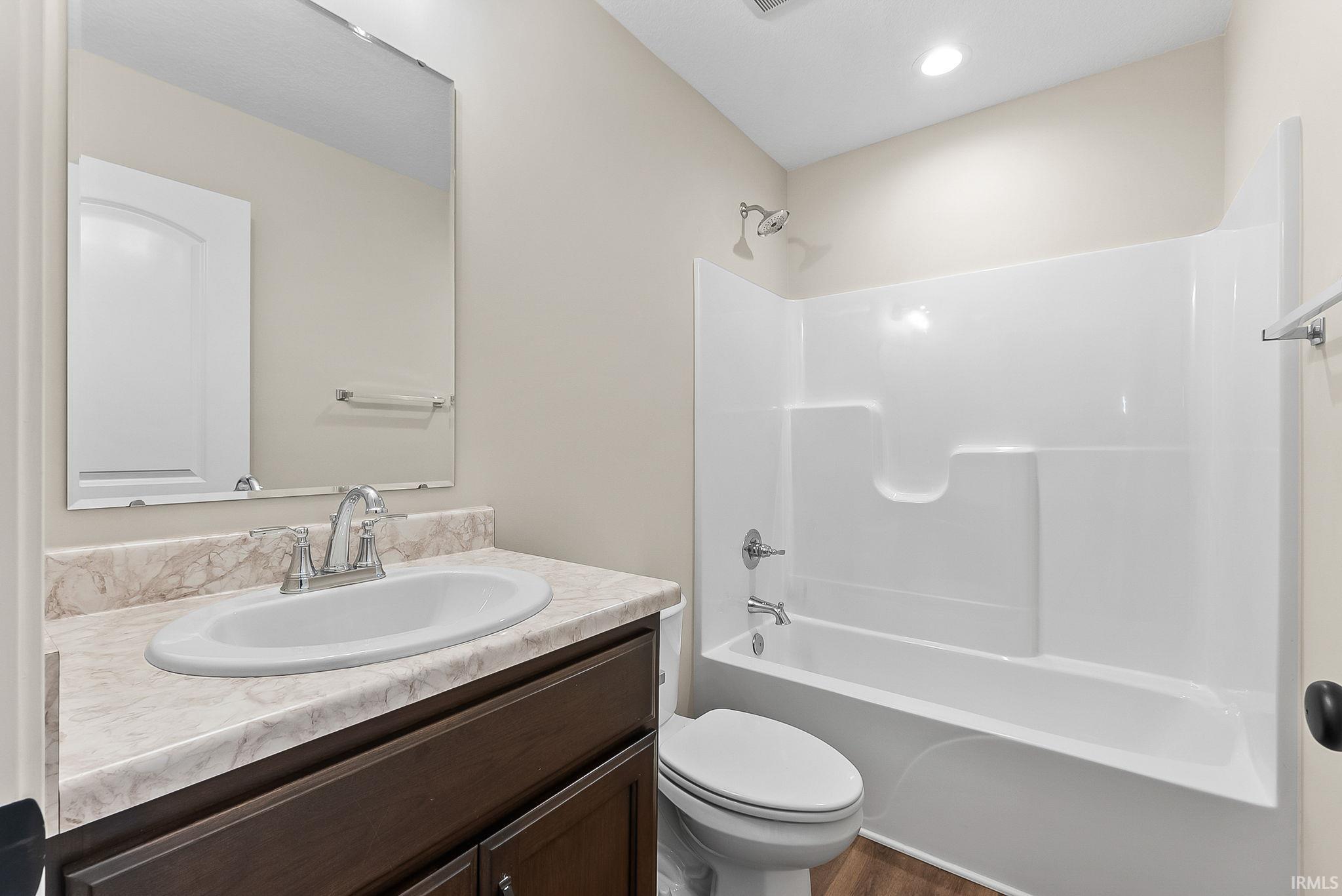 Modern bathroom featuring a dark wood vanity with a curved ceramic sink, marble-look countertop, and chrome fixtures