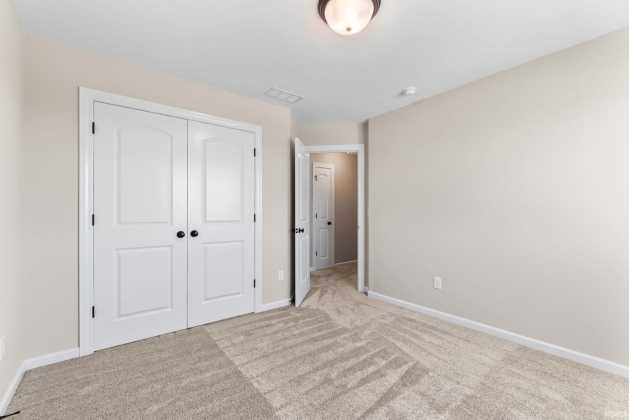 Spacious room featuring neutral carpeting and light-toned walls