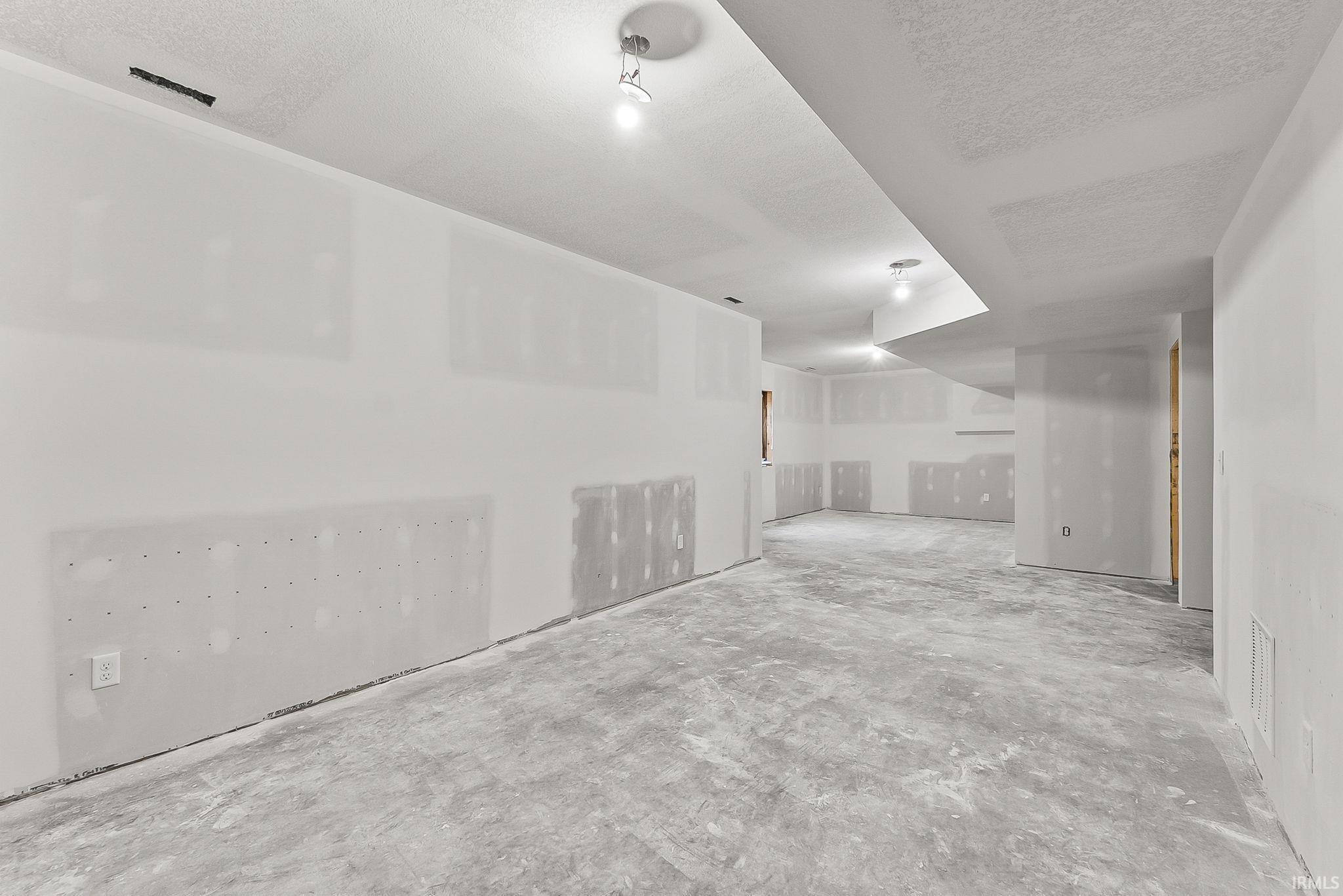 Expansive unfinished space with polished concrete flooring, recessed ceiling lighting, and white drywall construction