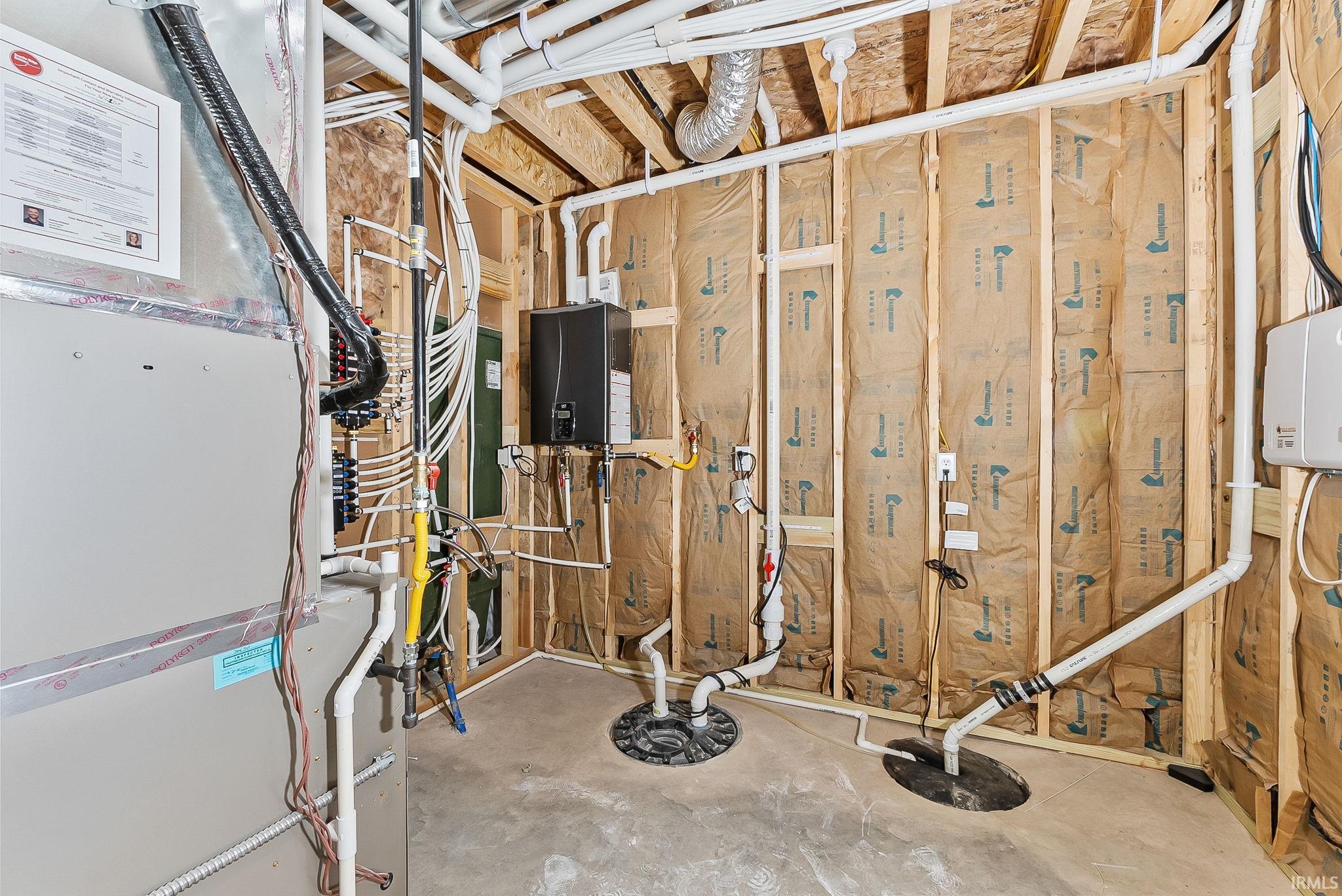 Utility room featuring a furnace unit, tankless water heater, comprehensive plumbing system, two sump pits, and wall insulation